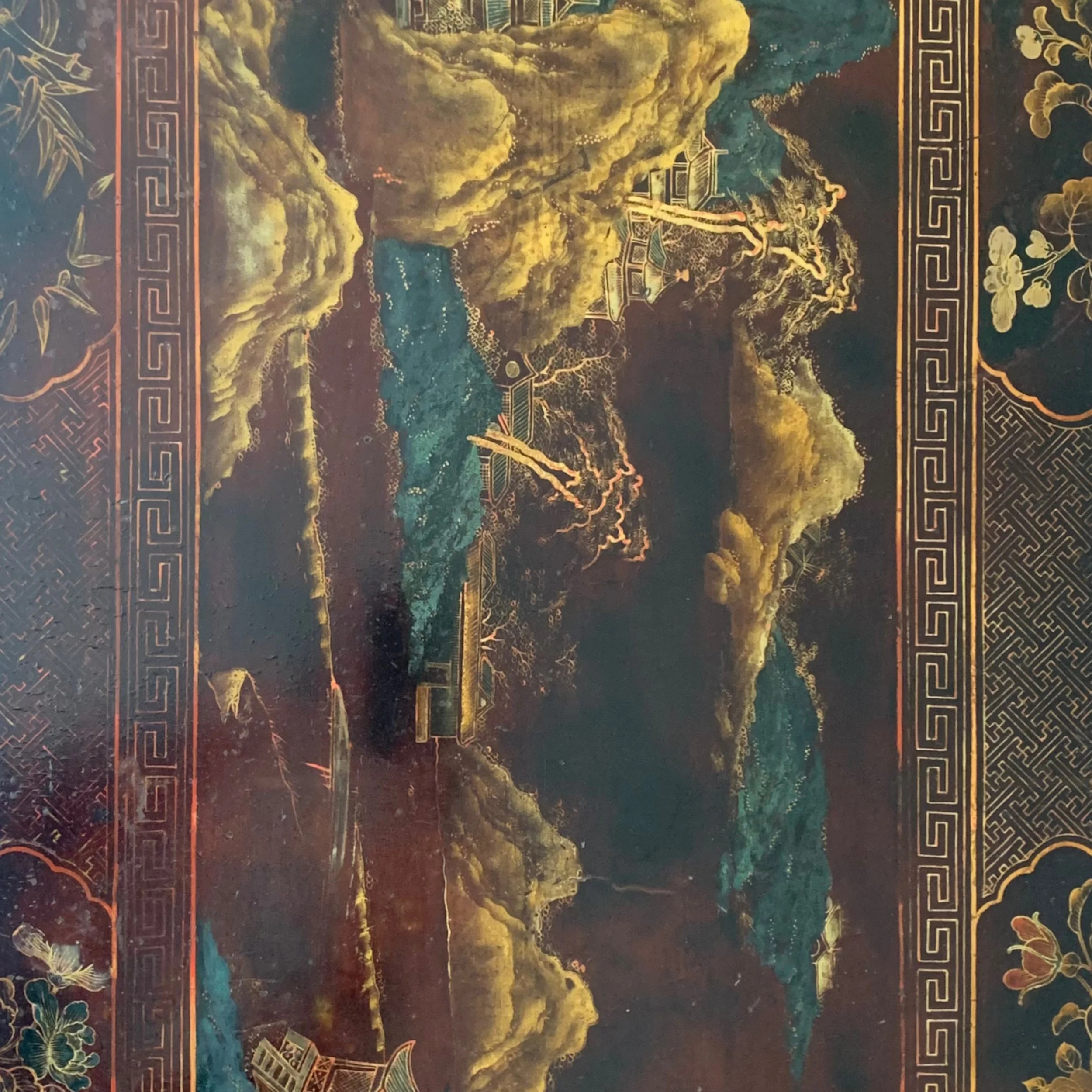 A traditional Asian landscape painting depicting mountains, a river, trees, and temples, with intricate gold and dark accents.