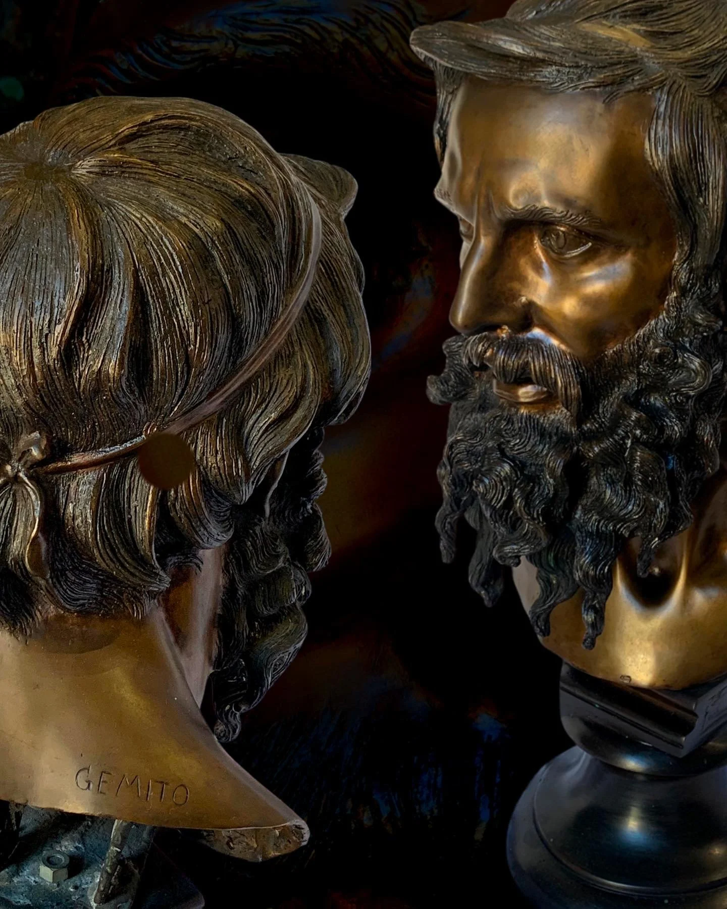 Bronze bust sculptures of a man and a woman with detailed hair and beards, facing each other.