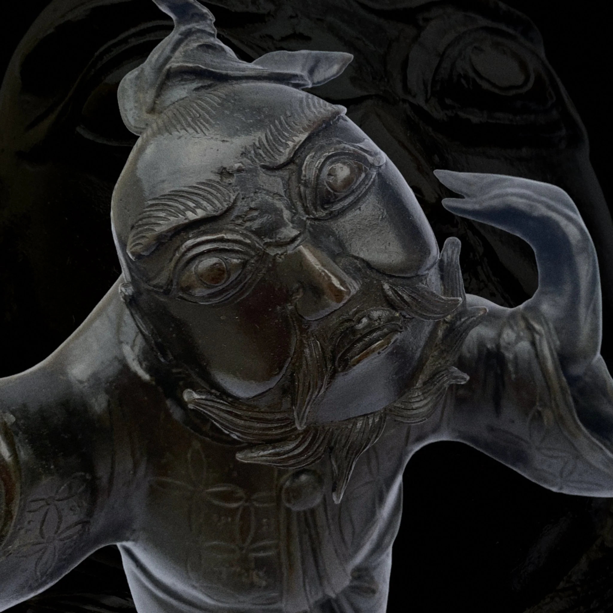 Close-up of a metallic sculpture of a bearded man with detailed facial features and traditional attire.
