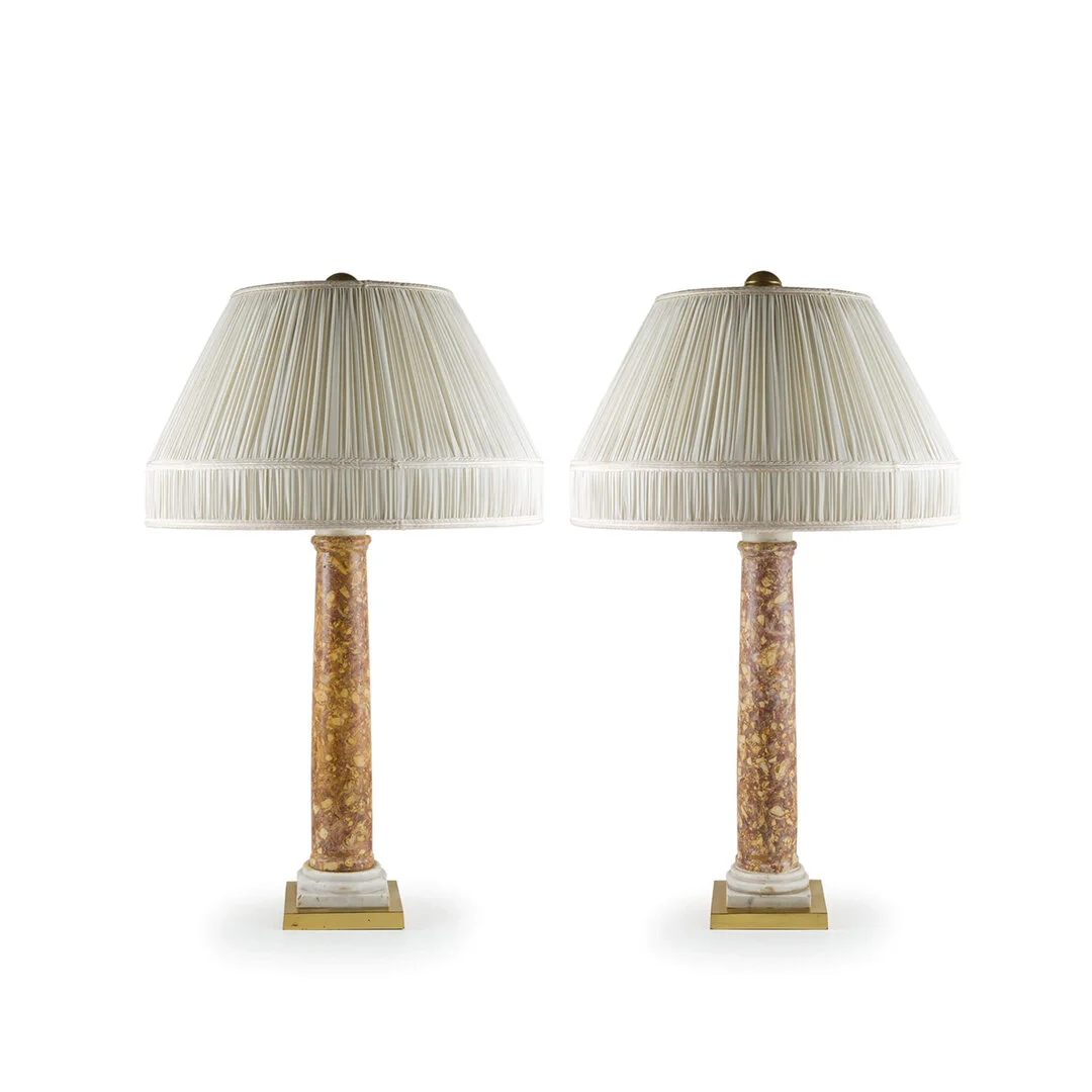 Two identical table lamps with cream-colored pleated fabric shades and marble-style bases, facing slightly toward each other against a plain white background.
