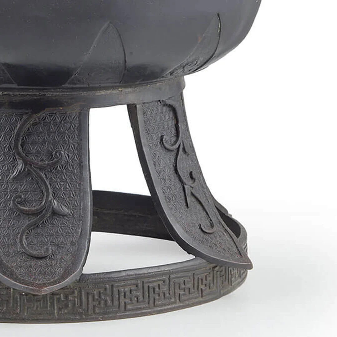 Close-up of a decorative wooden stool with intricate carvings on its legs and a patterned rim at the base.