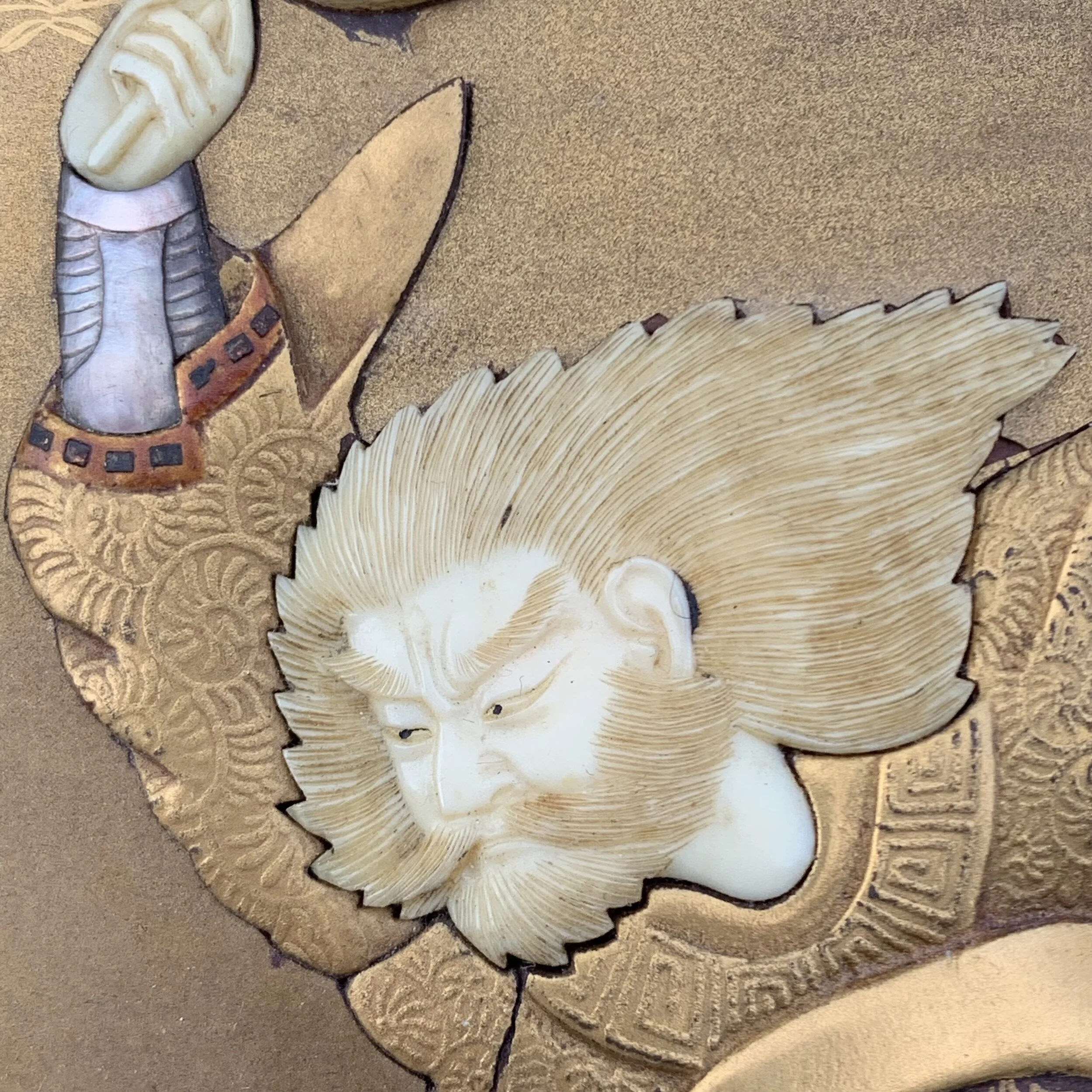 Close-up of a carved and painted wooden sculpture of a lion's head with detailed mane and fierce expression, surrounded by decorative elements.