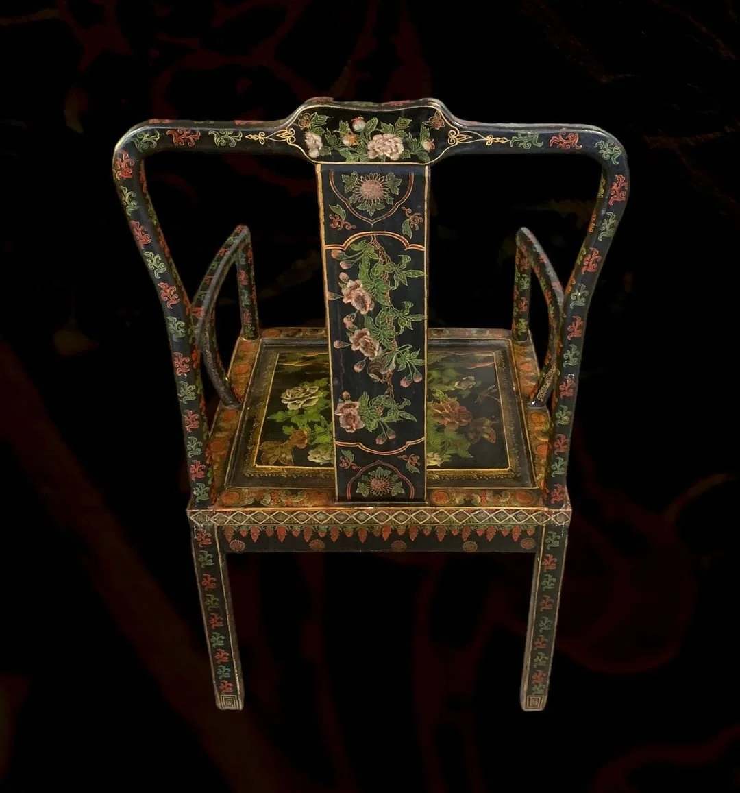 Decorative black lacquered chair with floral and geometric patterns in gold, red, green, and pink.