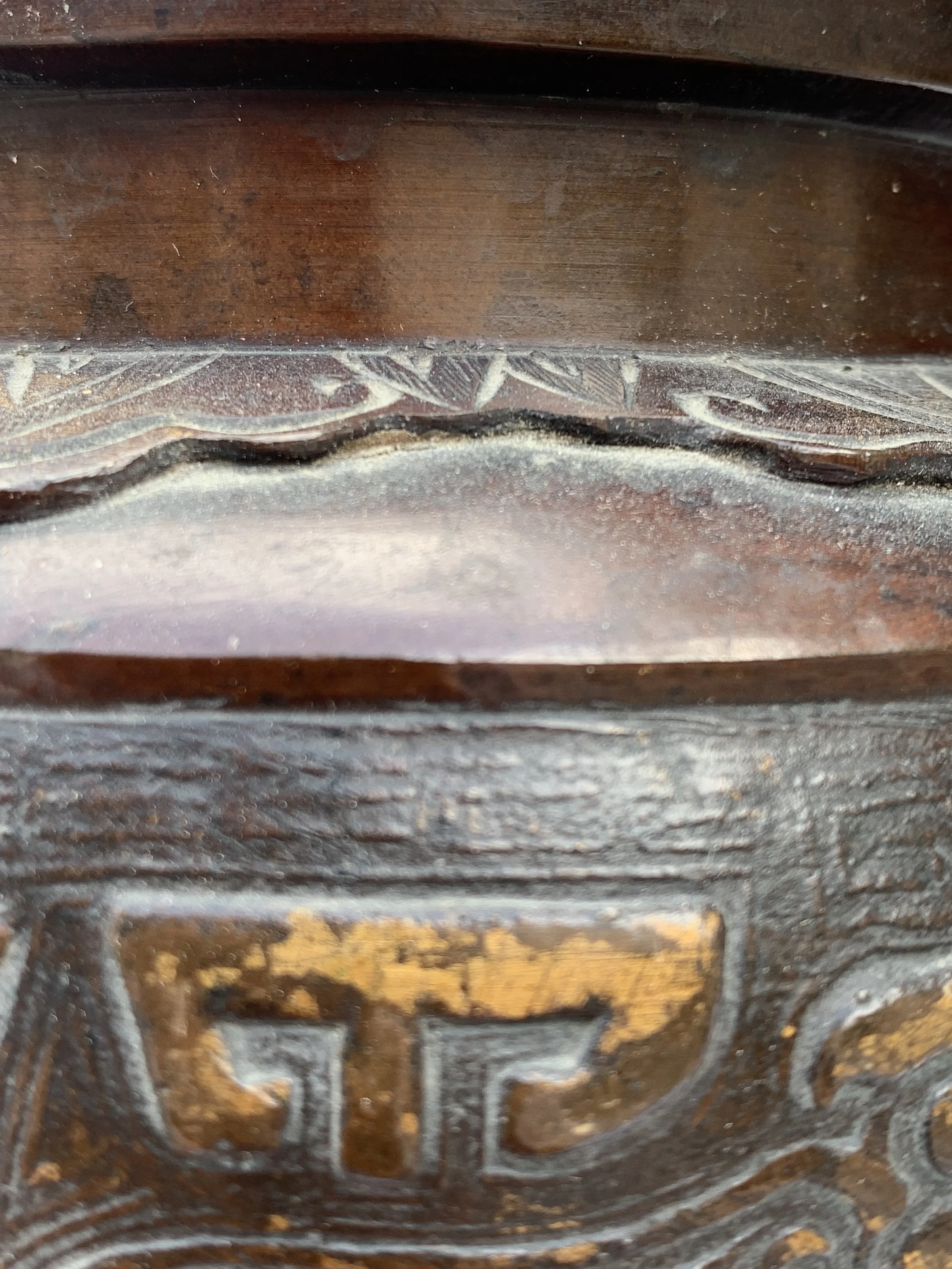 Close-up of carved wood with intricate patterns and the partially visible letters 'ET' on the surface.