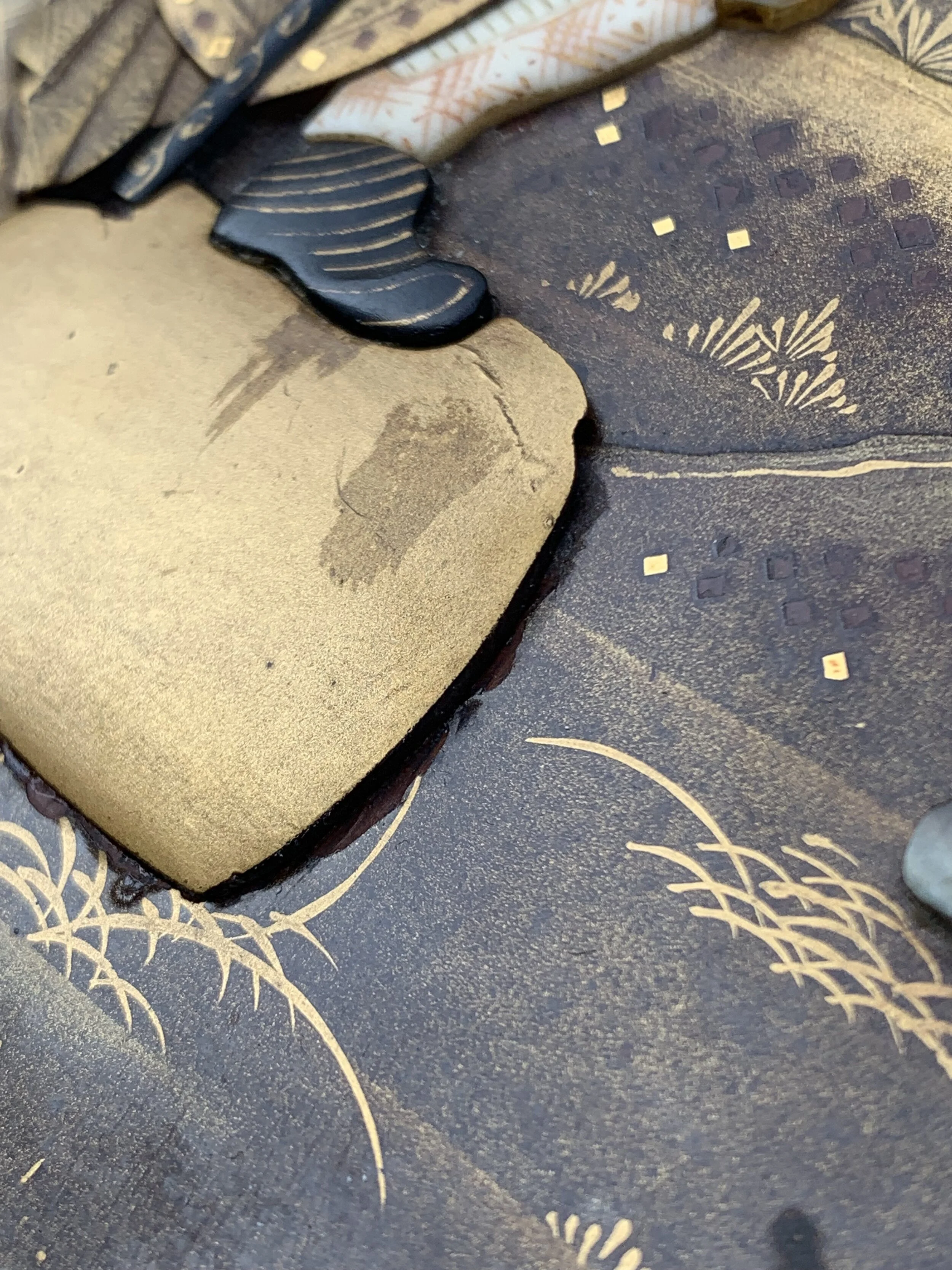 Close-up of a textured surface with abstract patterns, gold-colored accents, and a cutout shape with a shadow resembling a footprint.