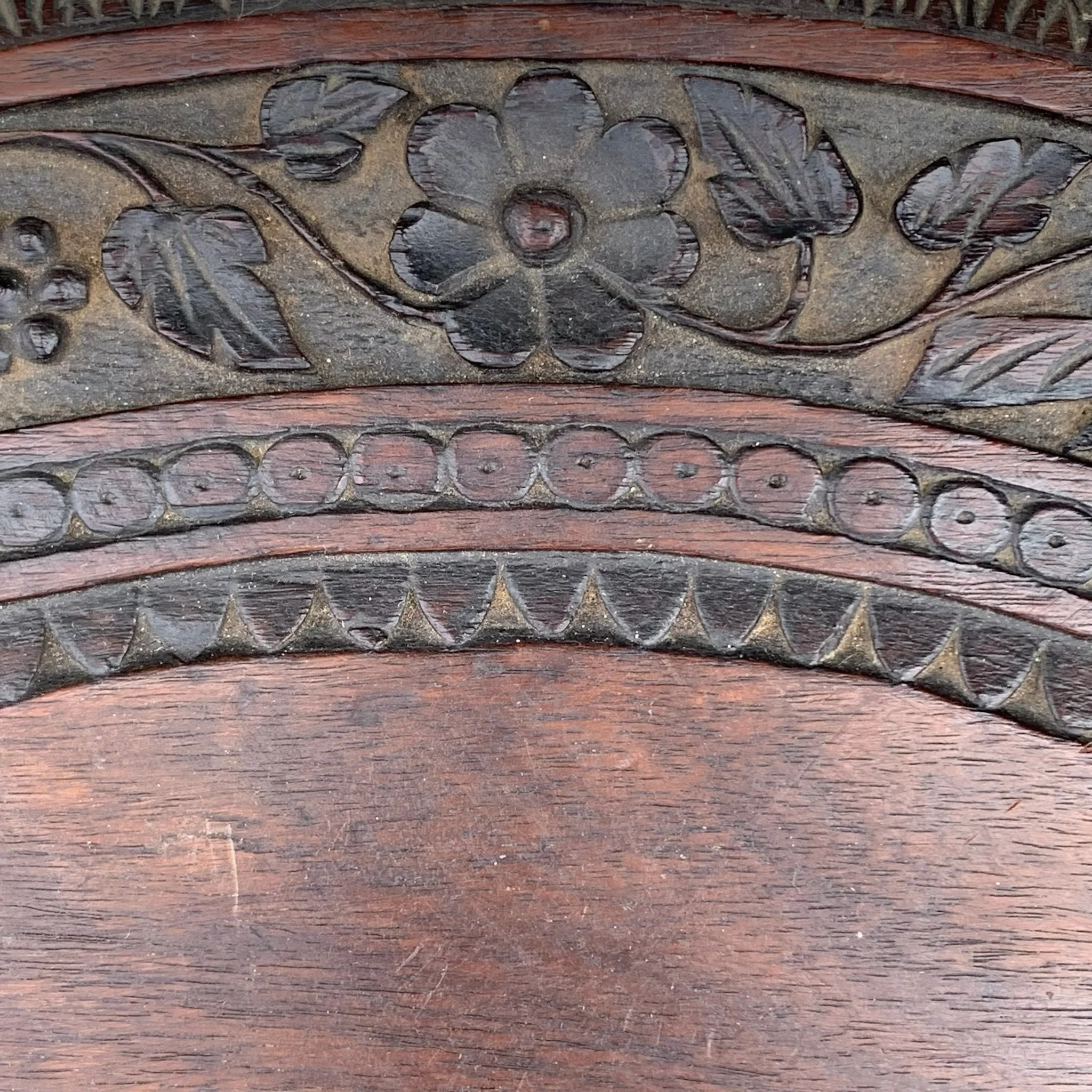 Close-up of a carved floral and geometric design on dark wood.