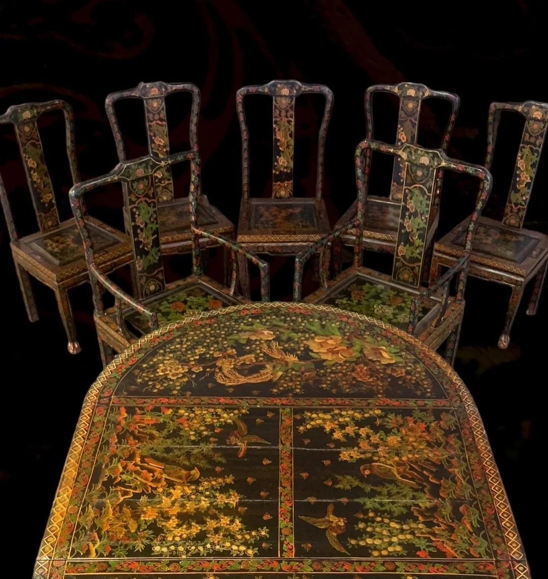 Set of six black lacquered chairs and a matching round table with intricate floral and bird designs, showcasing Asian-style decorative art.