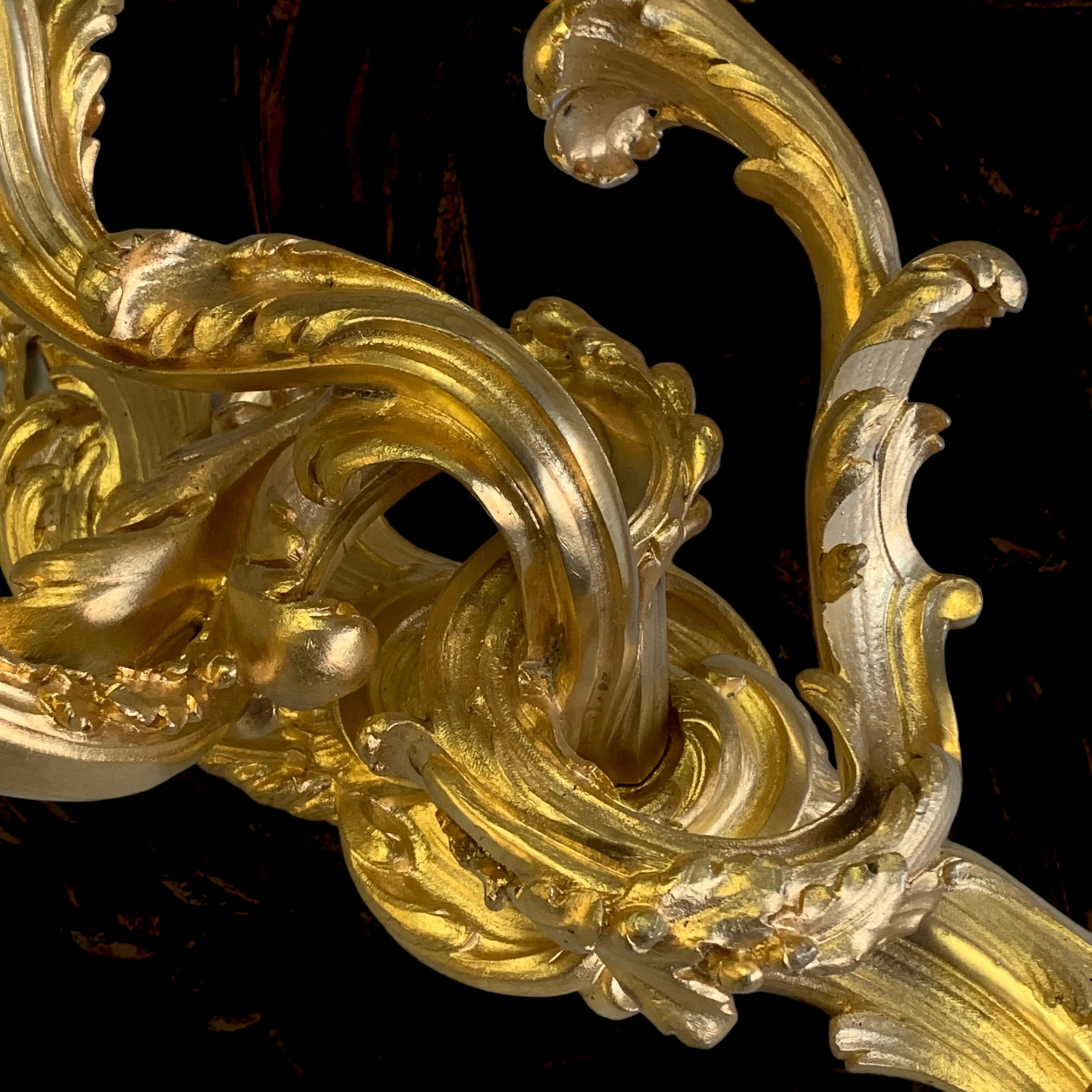 Close-up of an ornate, gold-colored decorative object with intricate scrollwork and detailing.