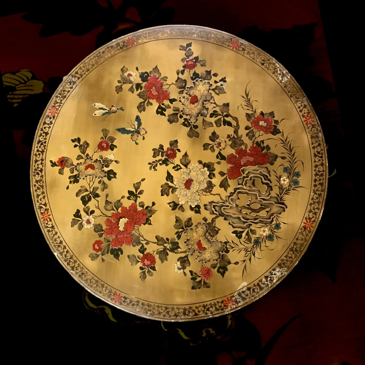 Decorative round tray with floral and butterfly patterns on a gold background, surrounded by an ornate border.