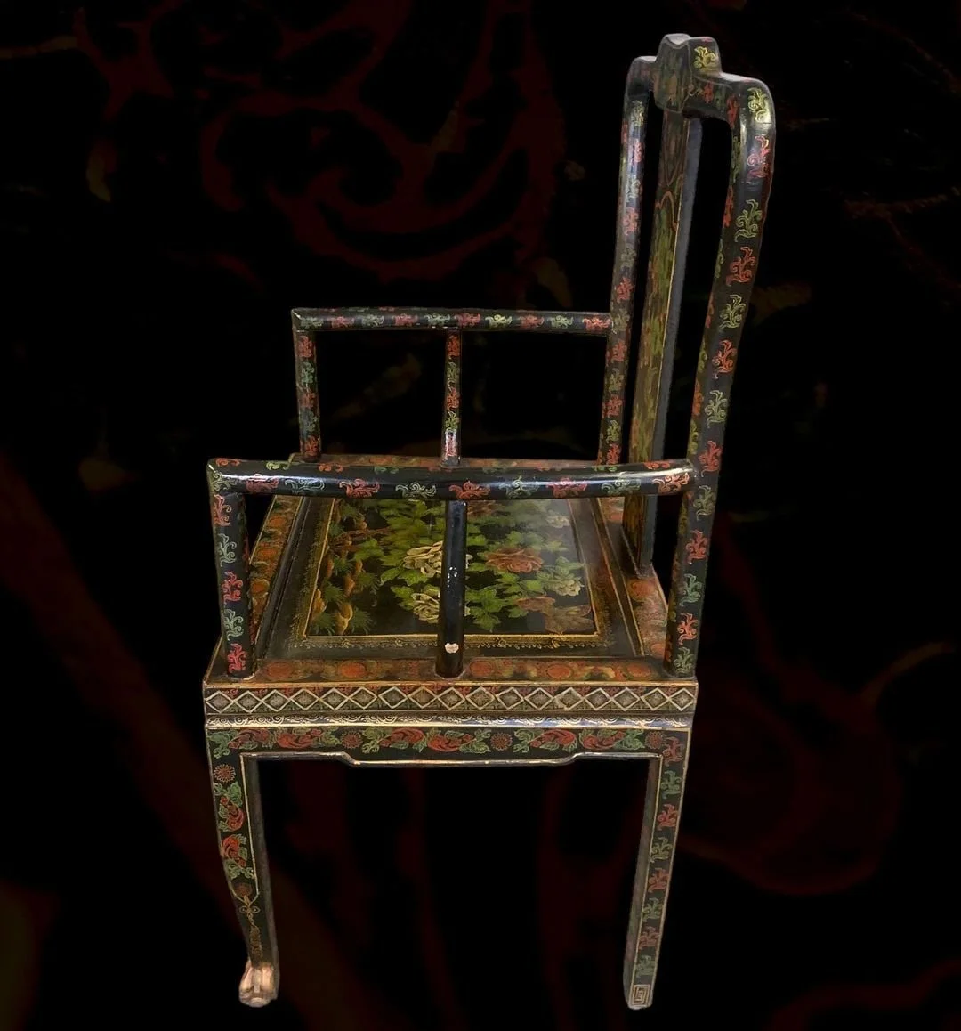 A small, ornate wooden chair with a painted floral design and a painted tabletop with floral motifs.