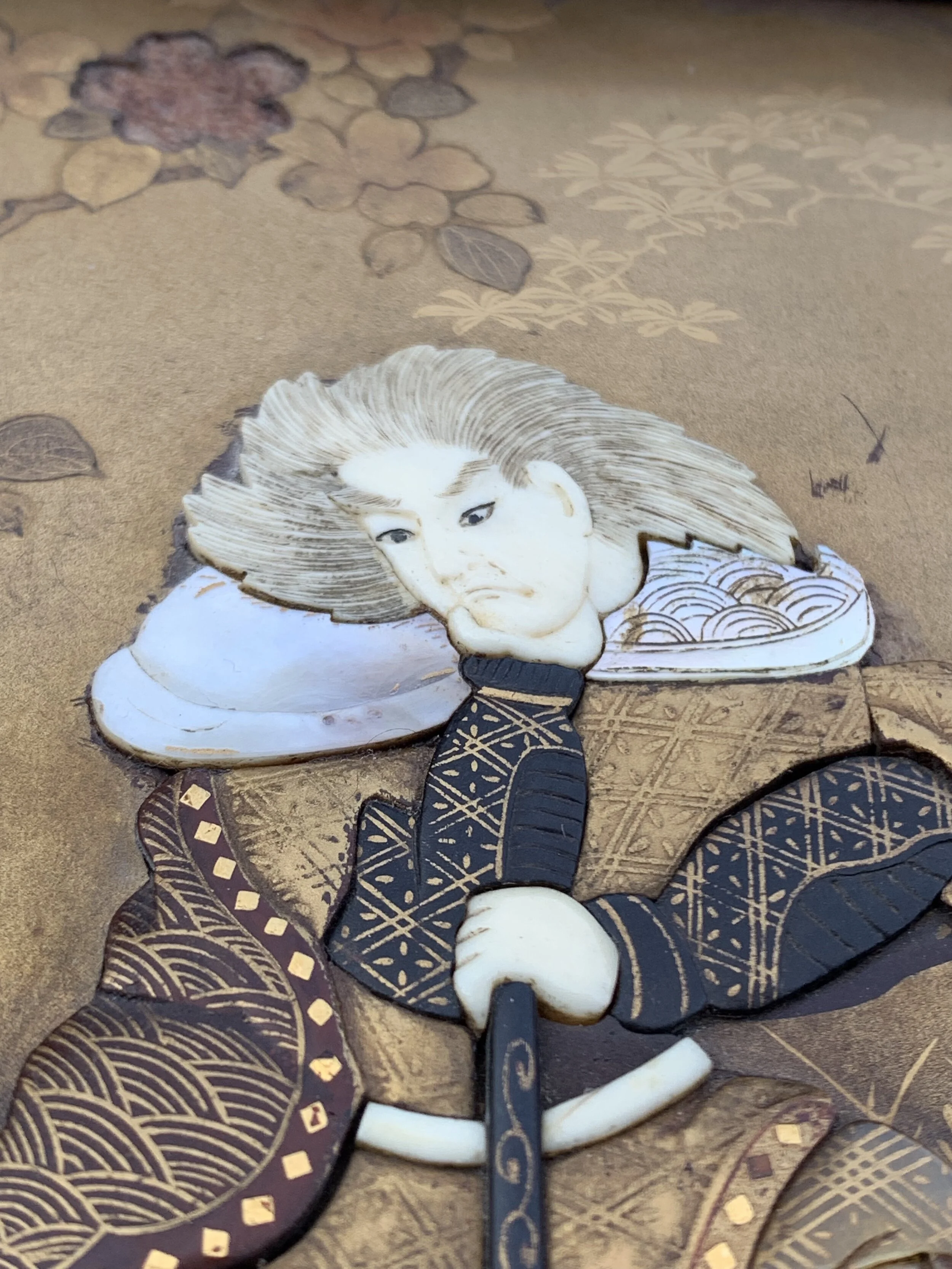 Japanese-style decorative art featuring a woman's face, long flowing hair, and traditional clothing, embedded in a textured background with floral patterns.