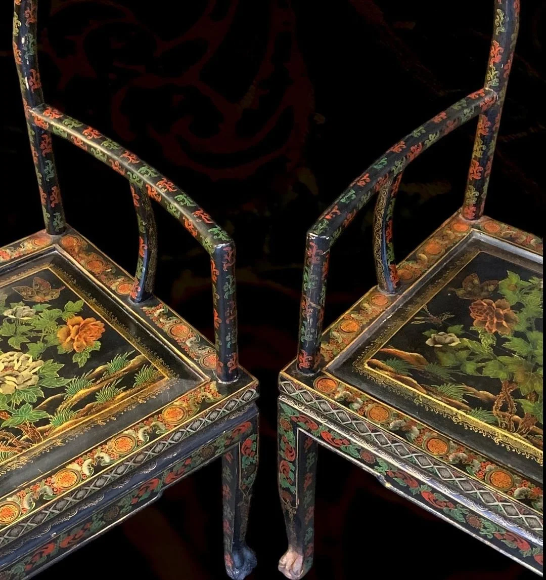 Two decorative black lacquered chairs with floral and butterfly motifs and detailed gold and red accents, featuring ornate floral images on the seats.