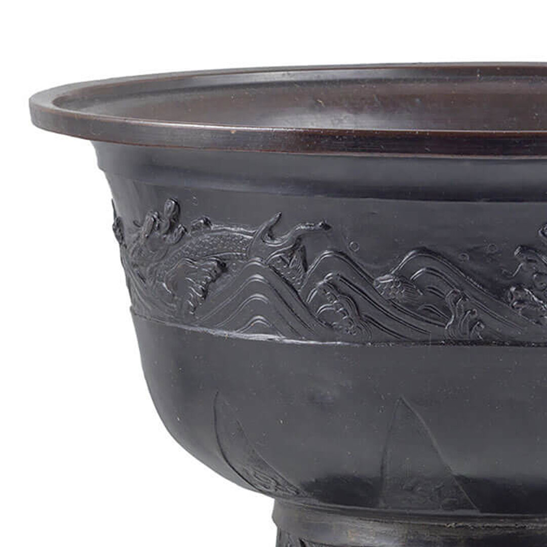 Close-up of a black ceramic bowl with intricate carved mountain and wave design.