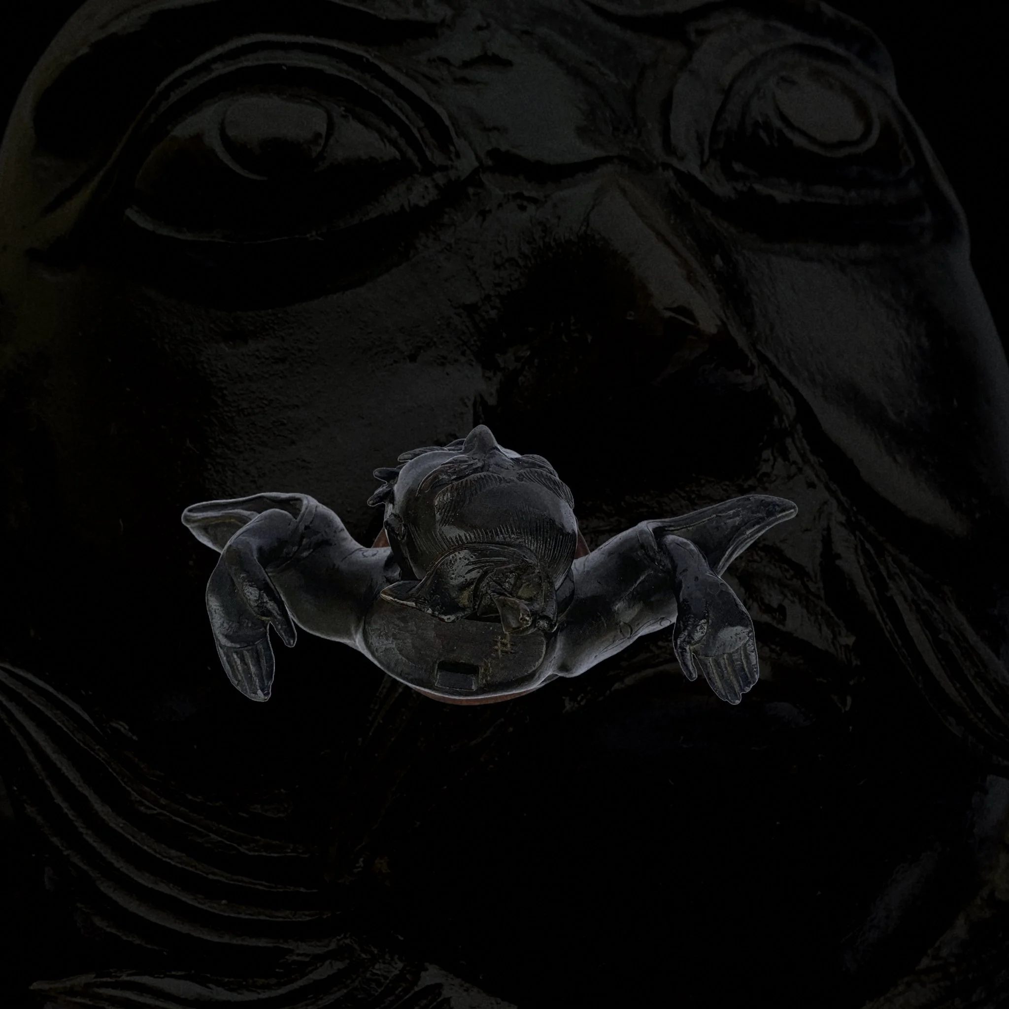 Close-up of a dark, glossy sculpture of a turtle with a smaller turtle resting on its head.