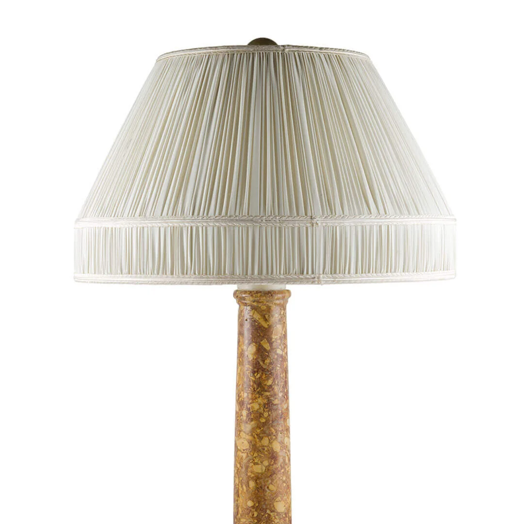 A table lamp with a pleated cream-colored lampshade and a marble-textured base.