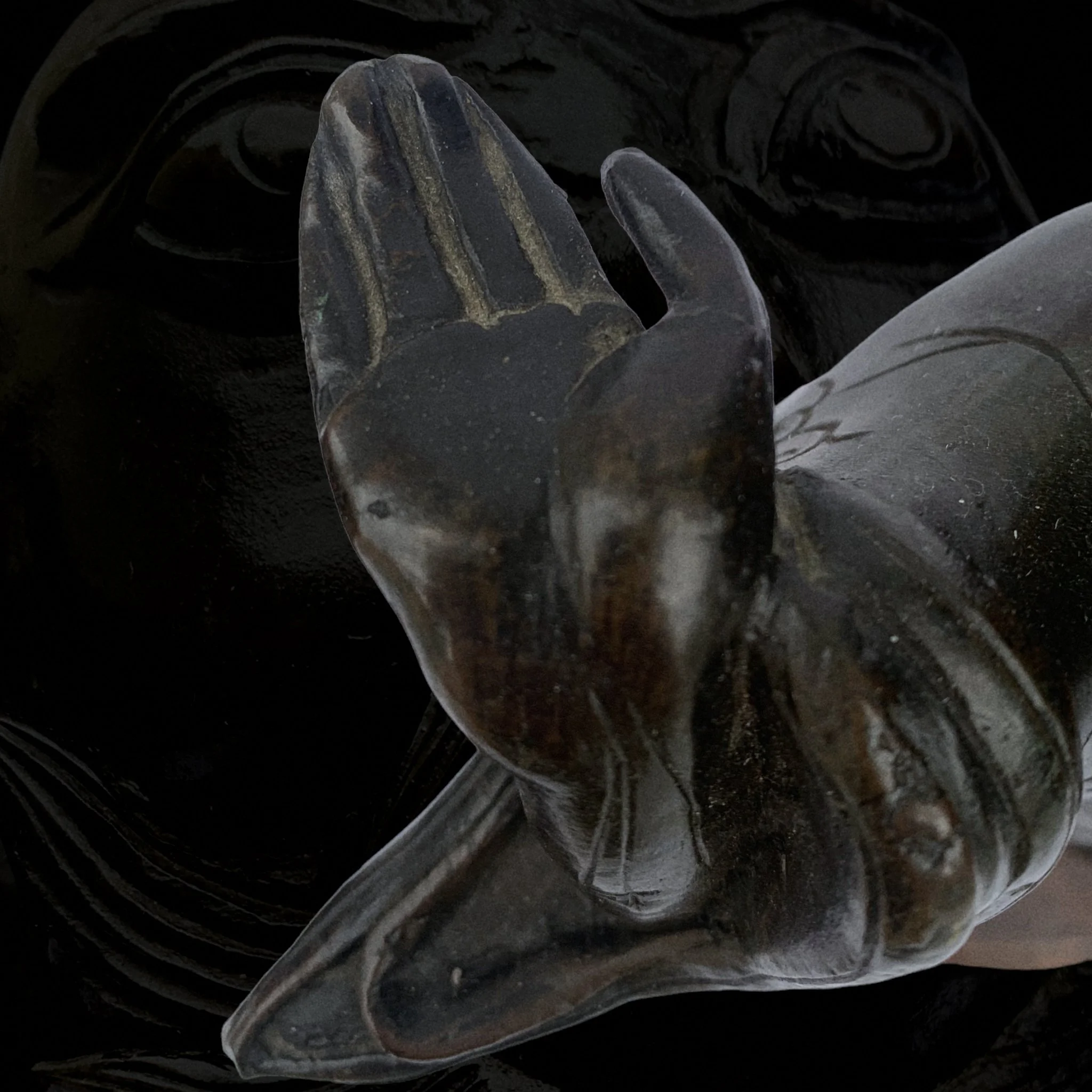 Close-up of a clear, glass monkey figurine with a smooth surface, placed on a dark background.