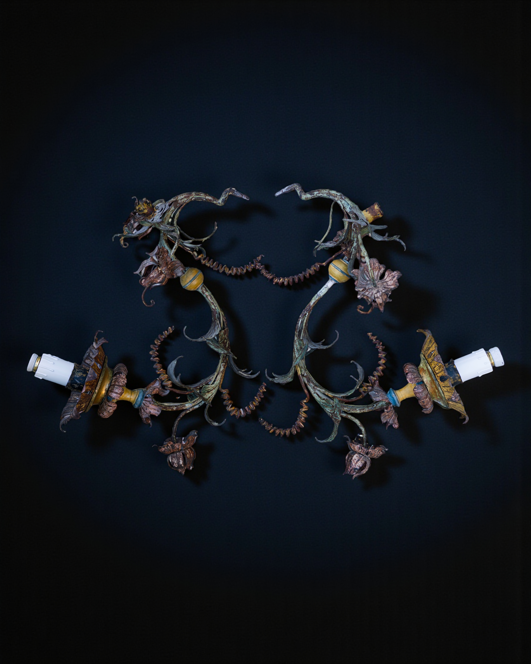 A pair of polychrome iron arms torcheres, in the shape of flowers and leaves