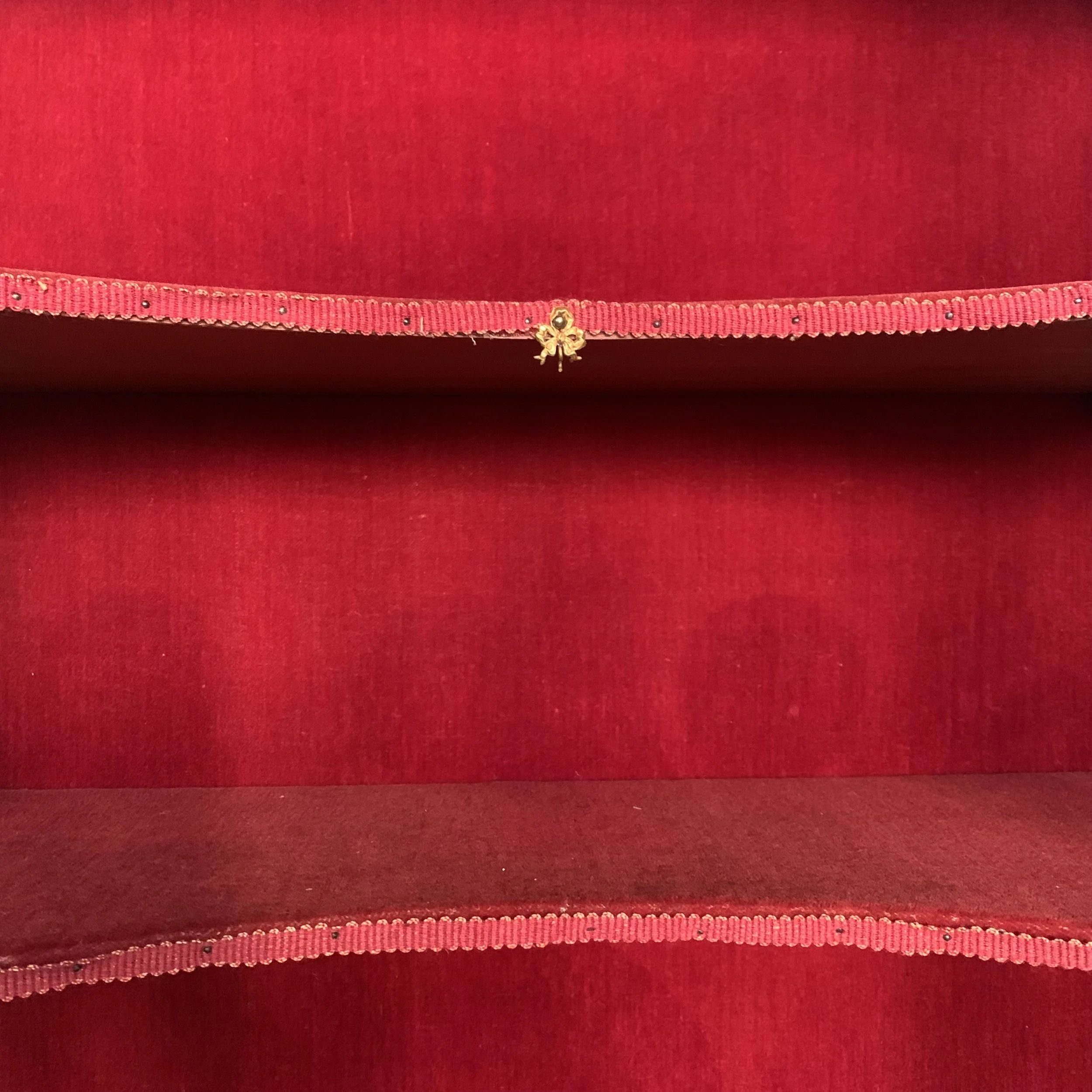 Close-up of red fabric with a pink ribbon and a small gold bow decoration.