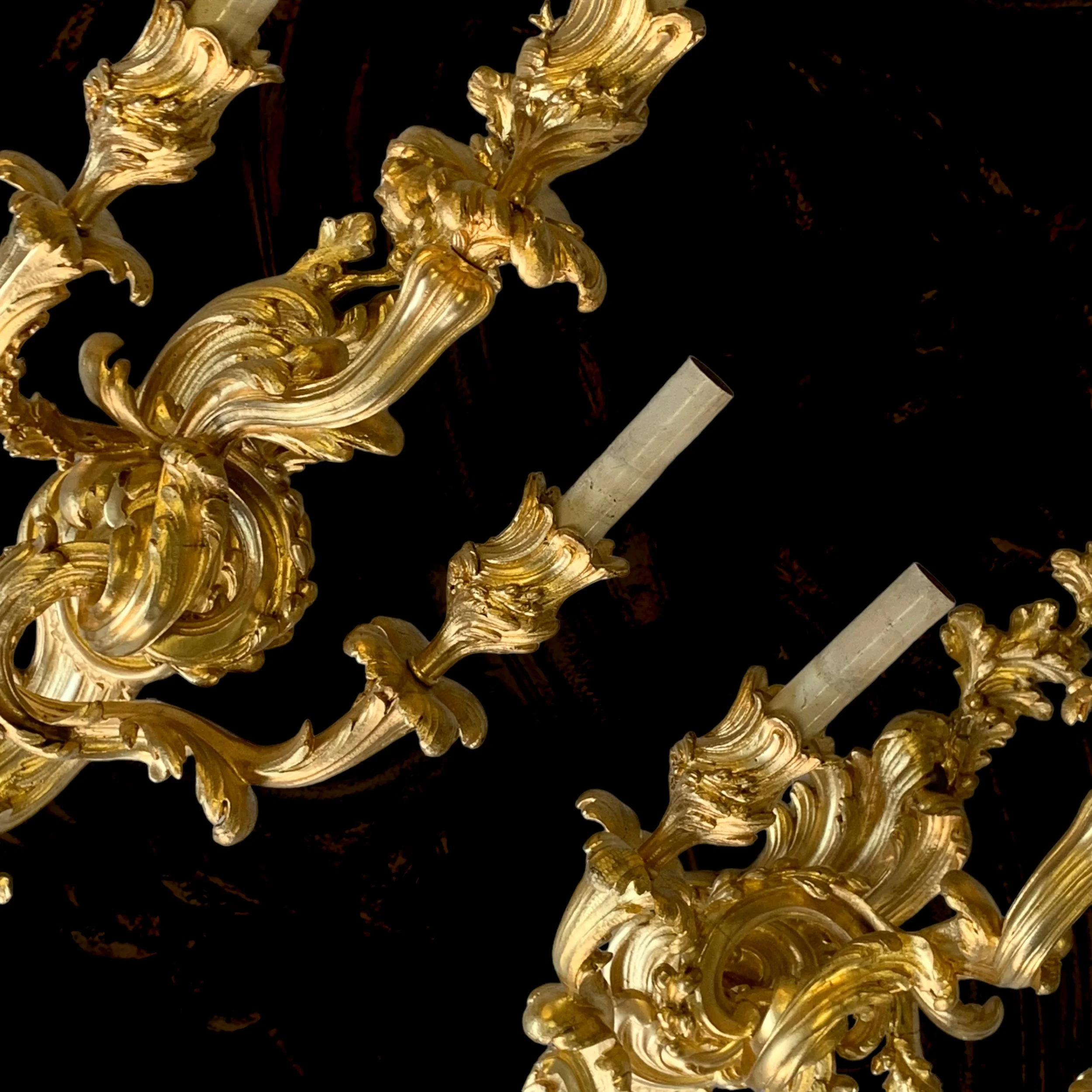 Close-up of a gold ornate chandelier with decorative scrollwork and candle-like light holders.