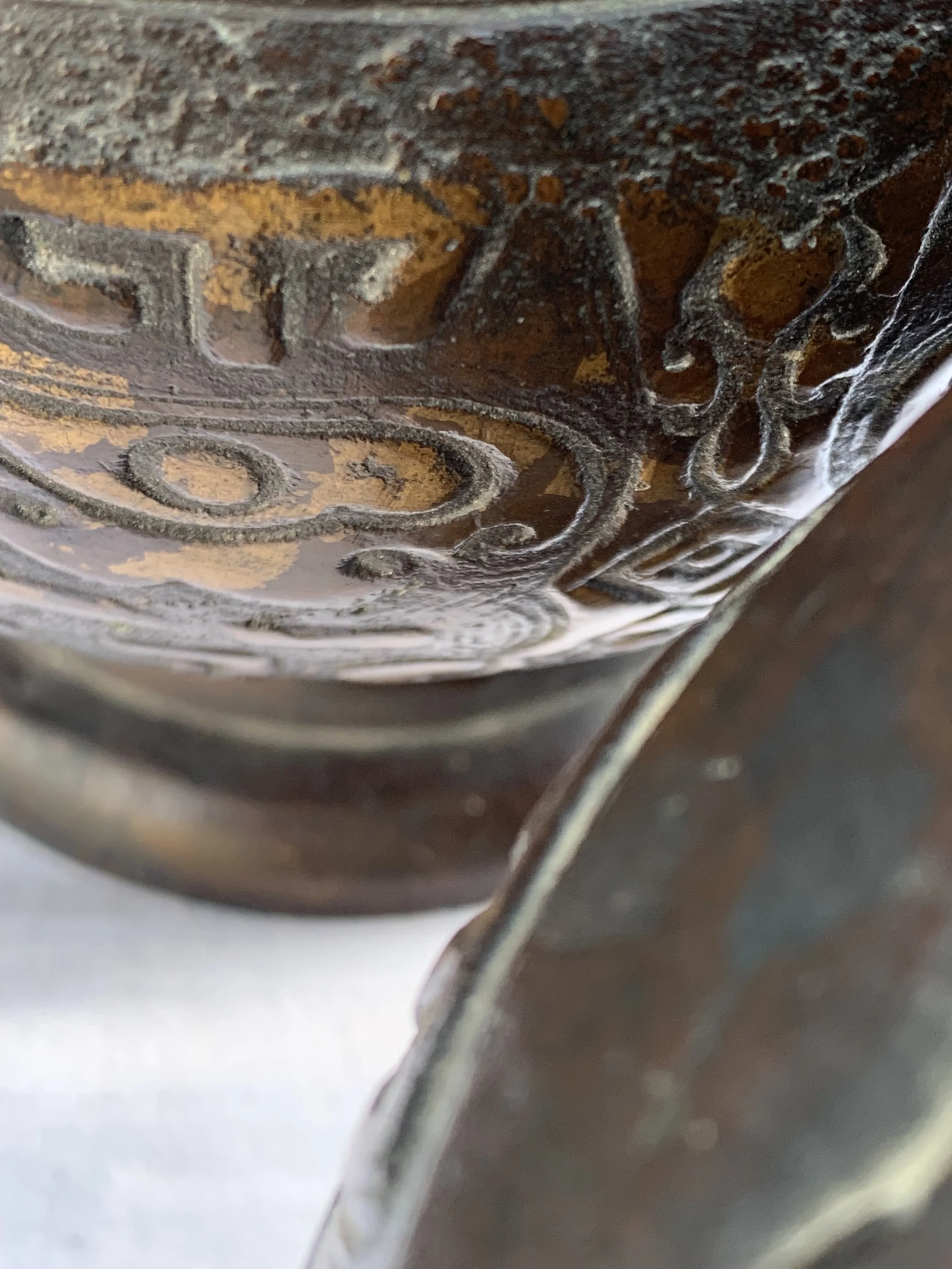 Close-up of an intricately carved dark wood surface, showing detailed patterns and designs.