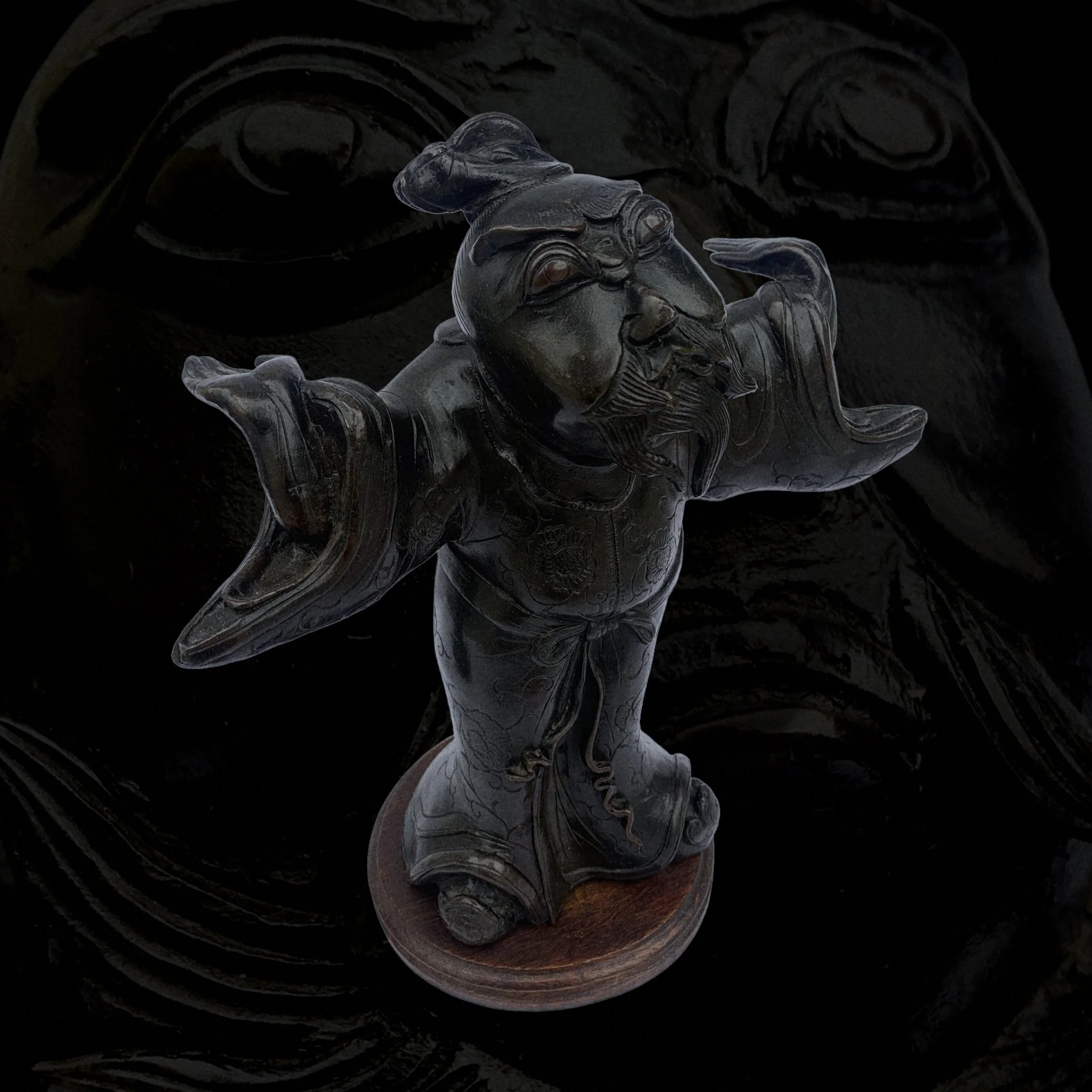 Carved wooden statue of a joyful, bearded man with arms outstretched, standing on a round base.