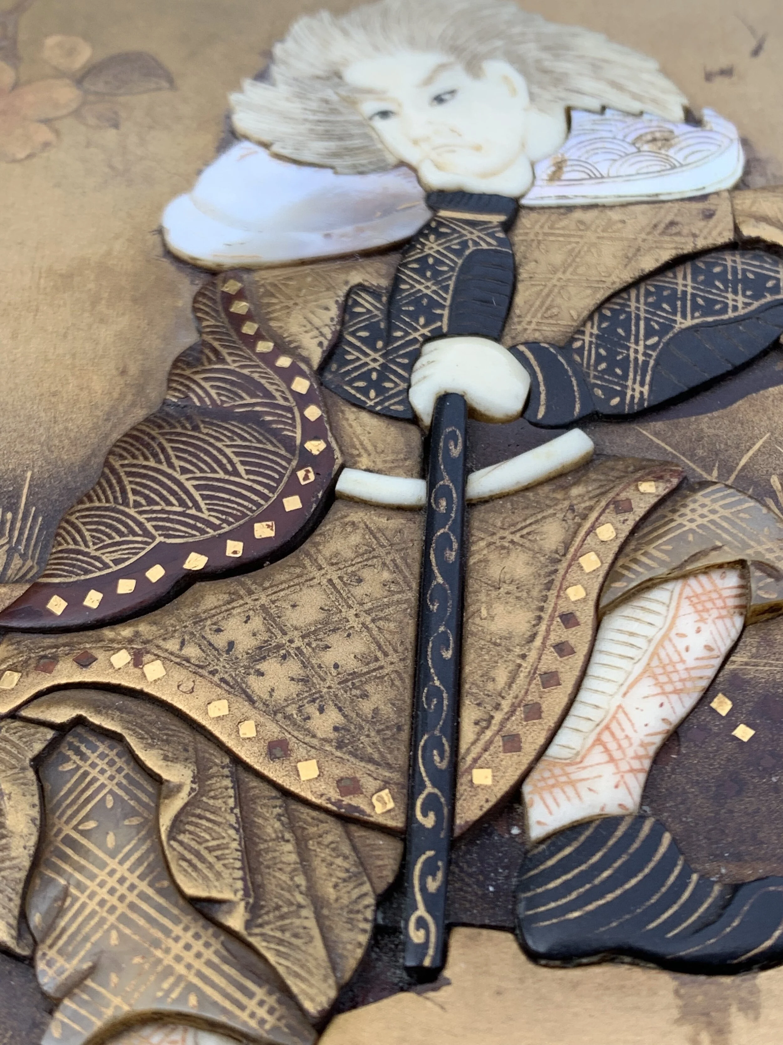 Close-up of a decorative dragonfly made from layered intricately patterned and colored materials, including a face of a woman as the dragonfly's head and detailed wings with various designs.