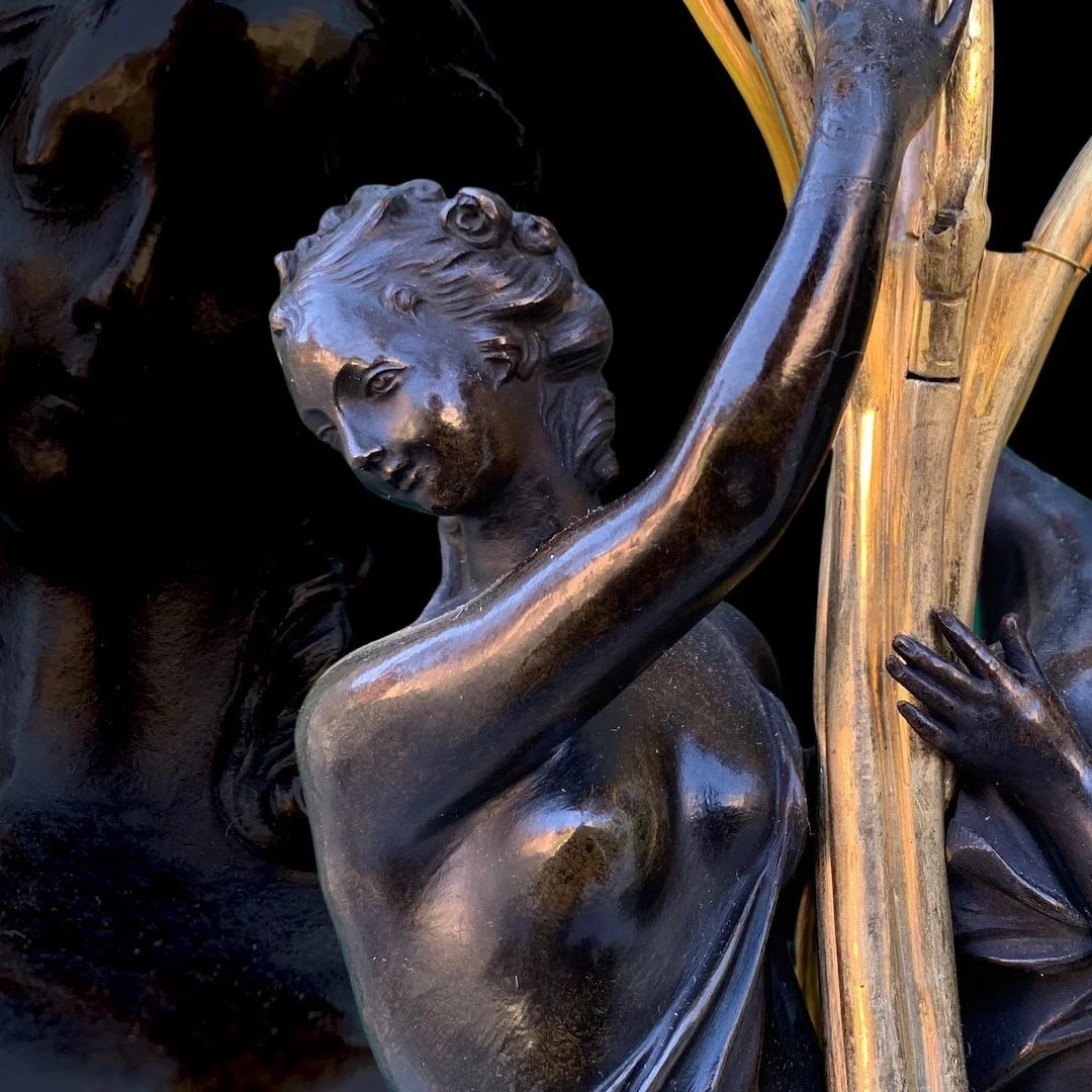 Close-up of a bronze sculpture depicting a woman with a contemplative expression, holding a branch or a piece of wood.