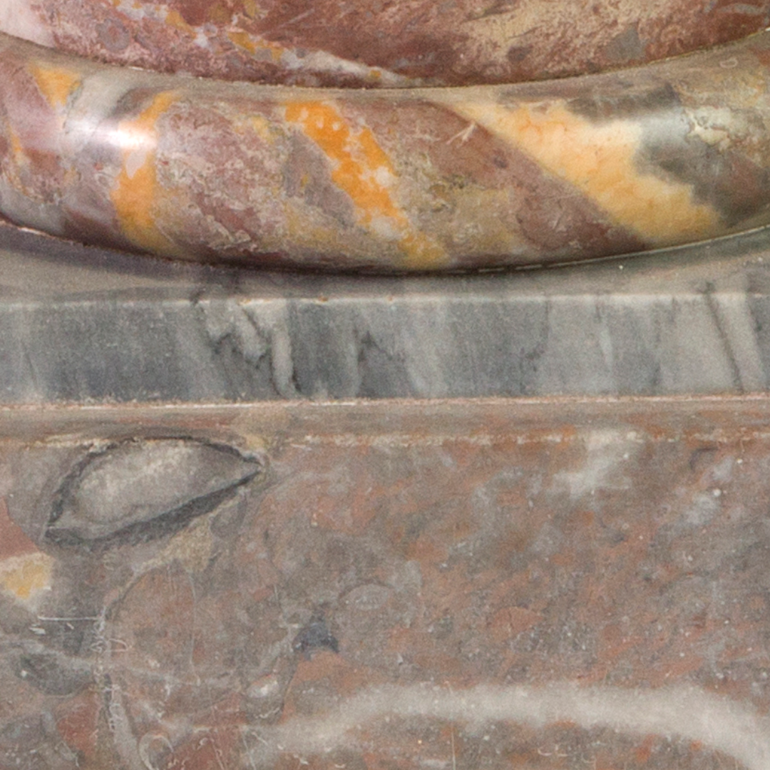 Close-up of a marble statue base with a detailed carved eye and textured surface.