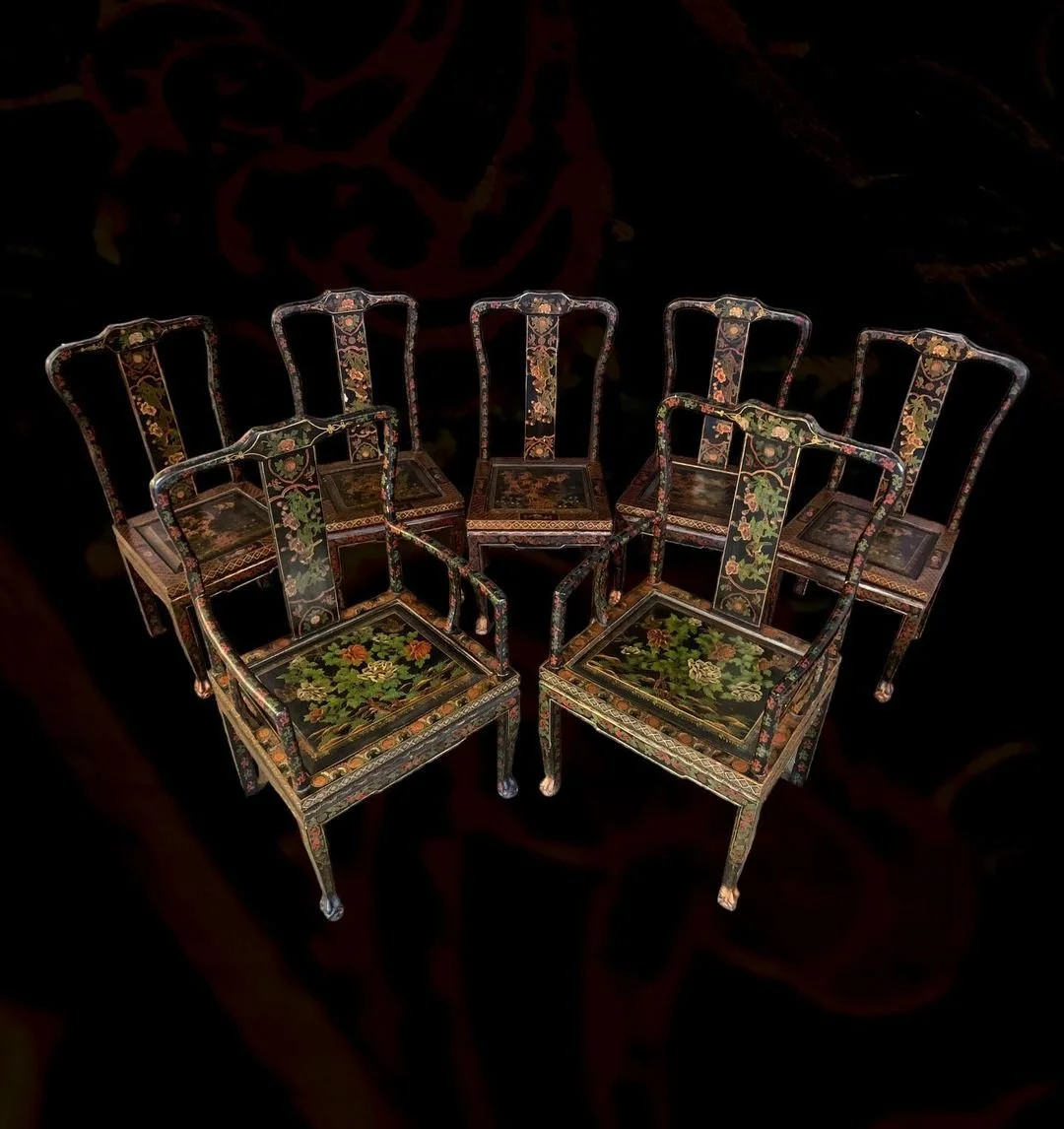 Collection of six antique wooden chairs with floral and decorative patterns, arranged on a dark background.