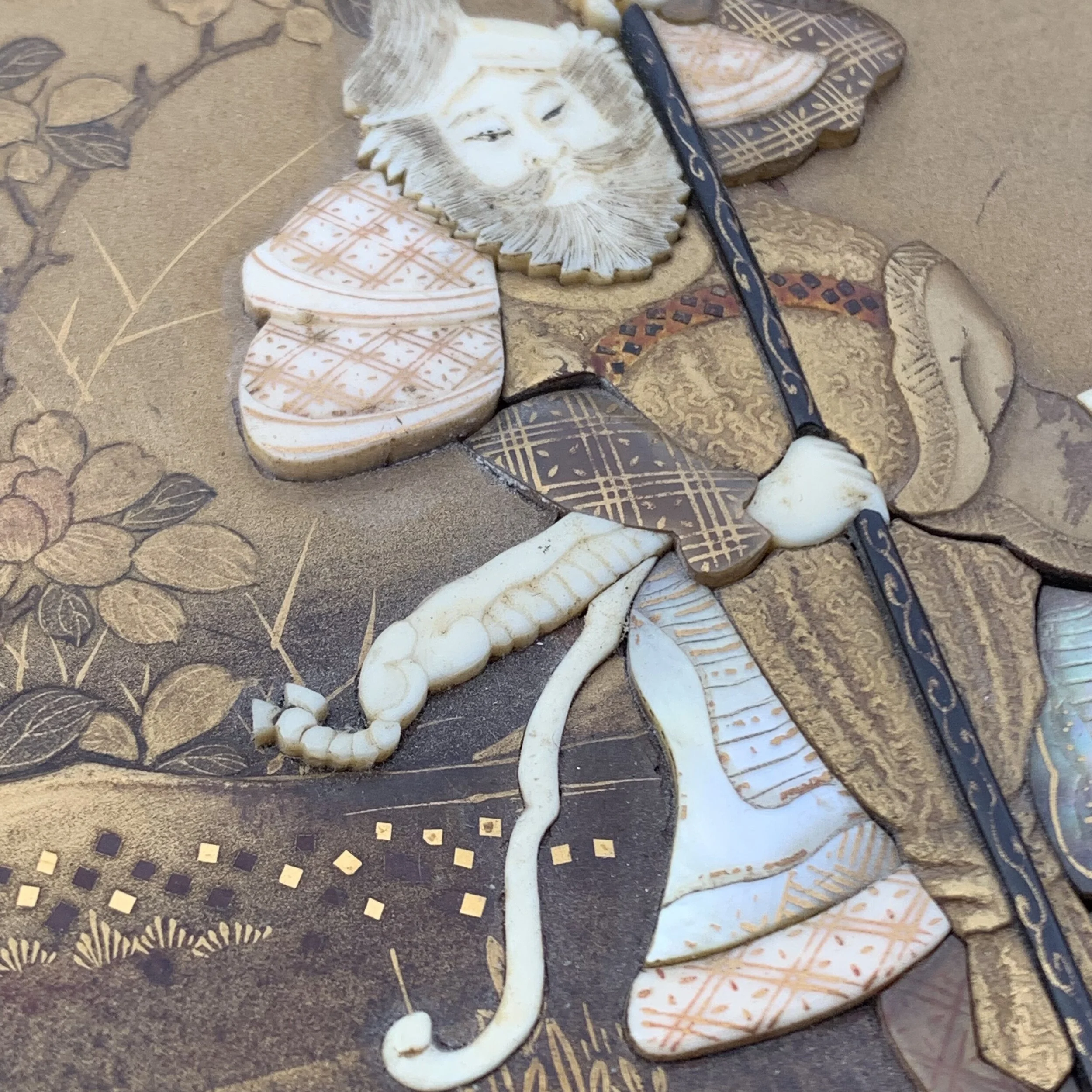 Close-up of a decorative artwork featuring an elephant made of carved stone tiles, with a painted face in the style of a traditional Asian elephant, on a textured background with floral and geometric patterns.