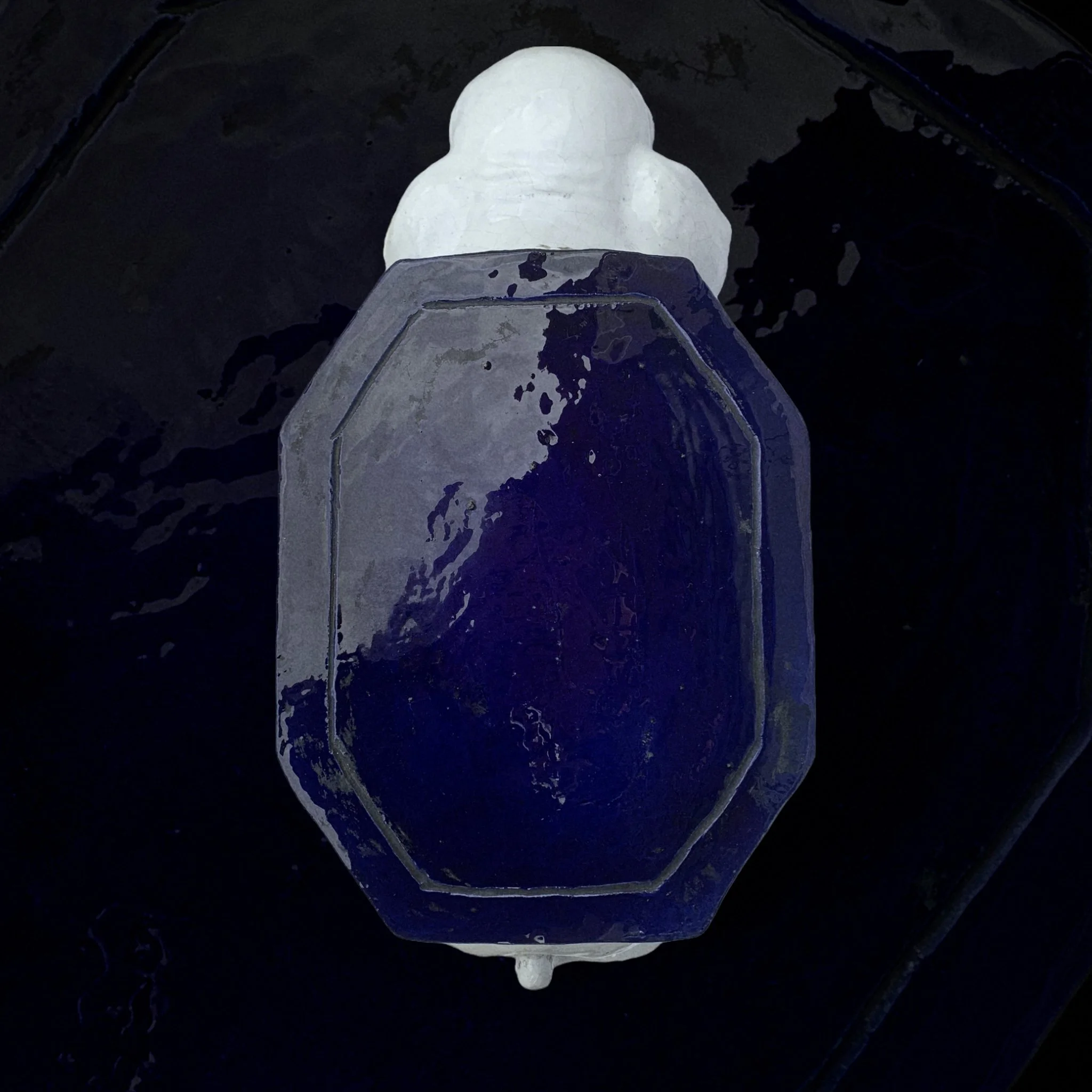Top view of a glass soap dispenser with white soap inside, placed on a black surface.