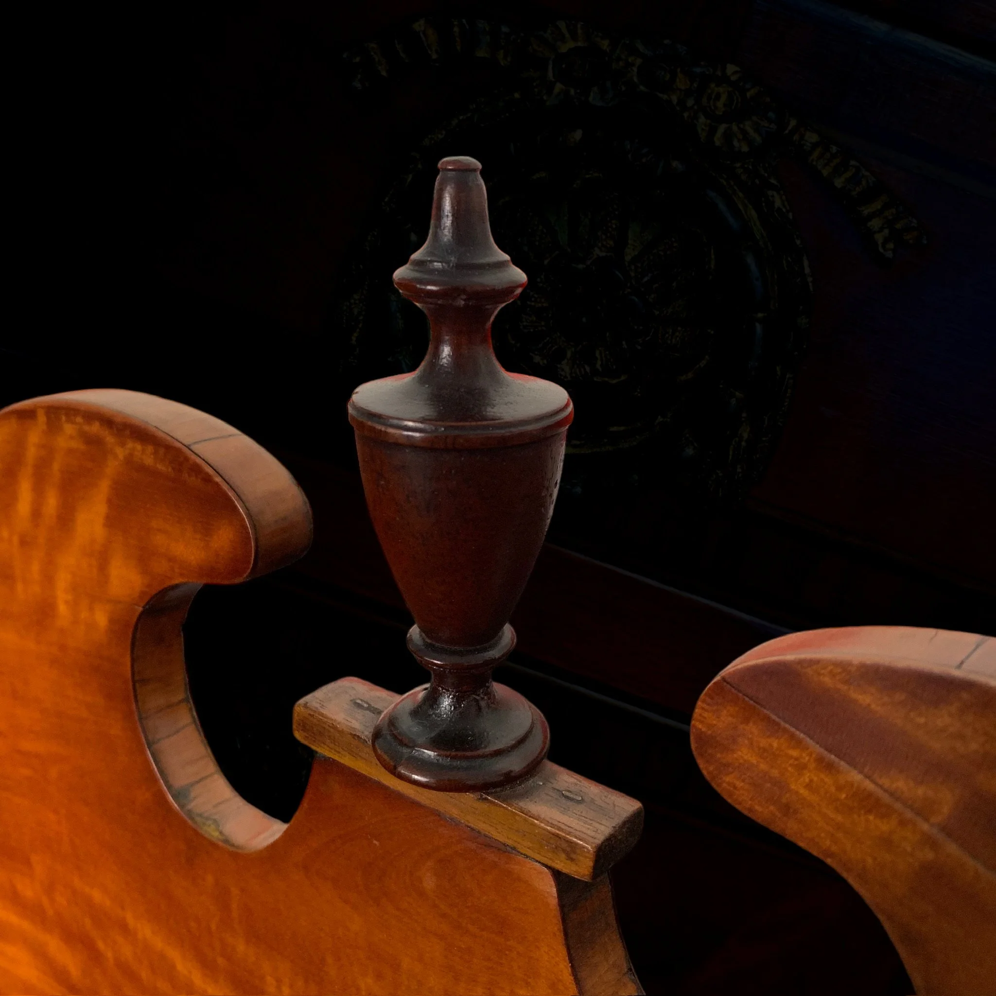 A dark, ornate wooden desk with a brown wooden chair and a vintage glass or ceramic urn in the center.