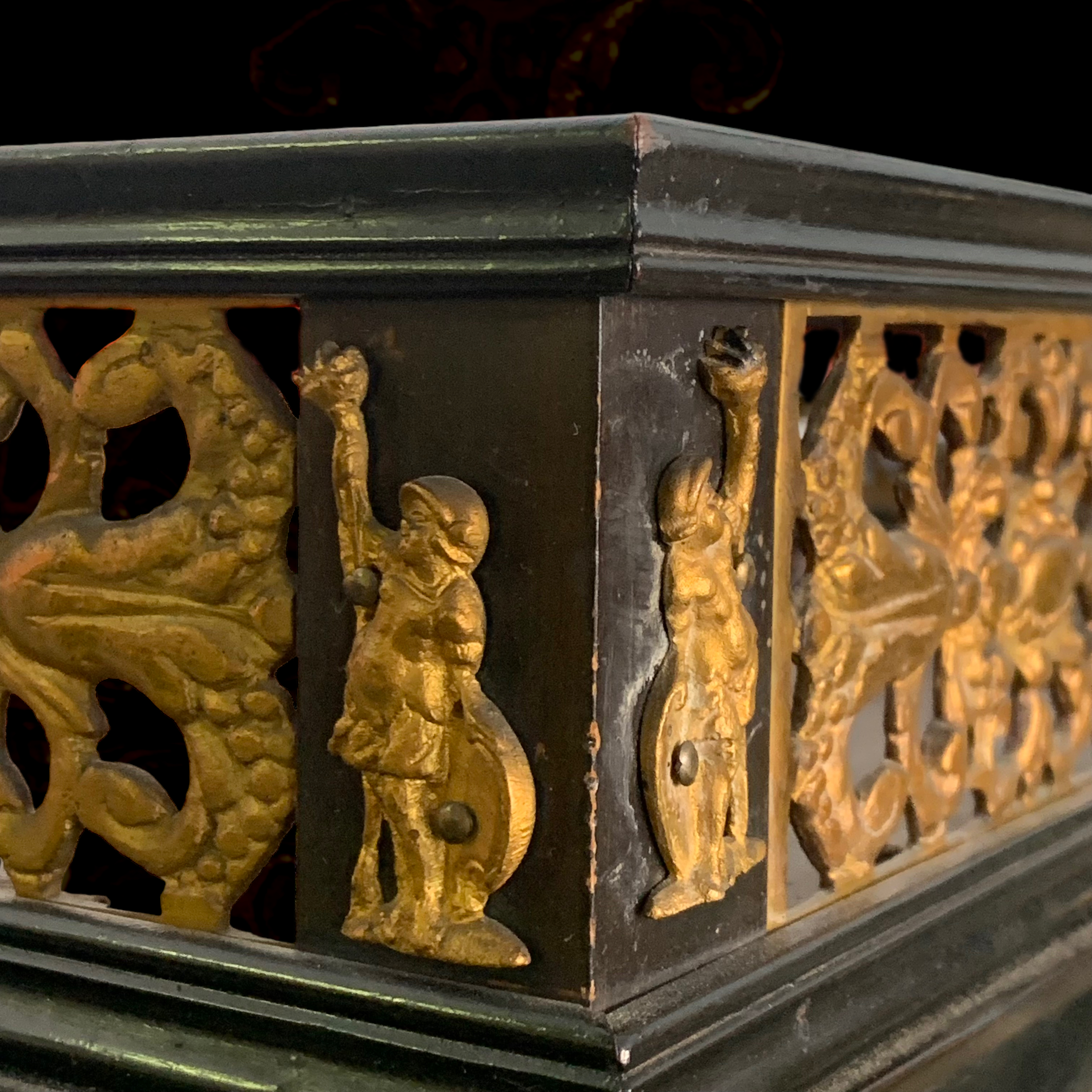 Close-up of a decorative wooden box with gold painted figures of children and animals on a black background.