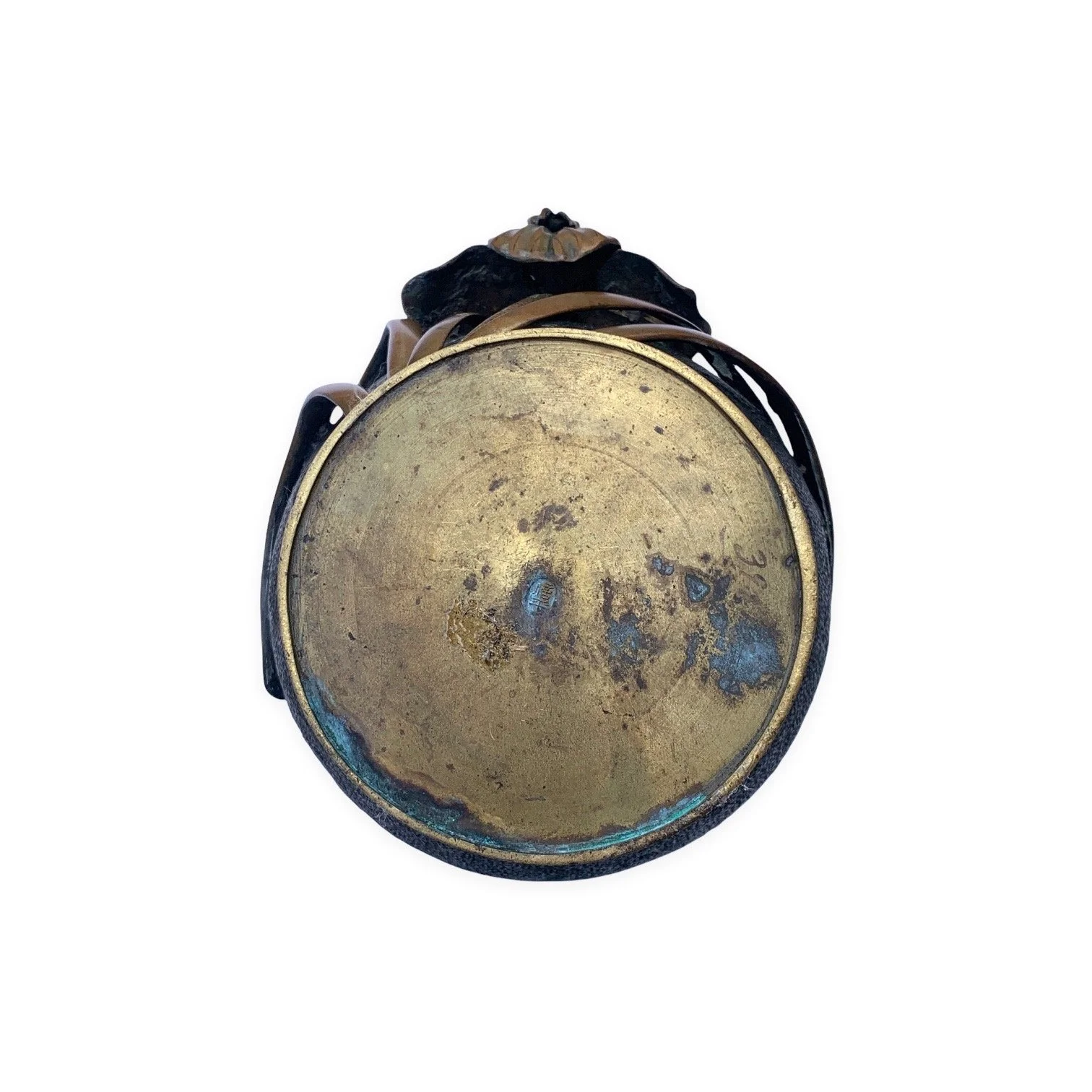 Close-up of the bottom of an old, round, metallic object with a worn, tarnished surface and darkened edges, against a plain white background.