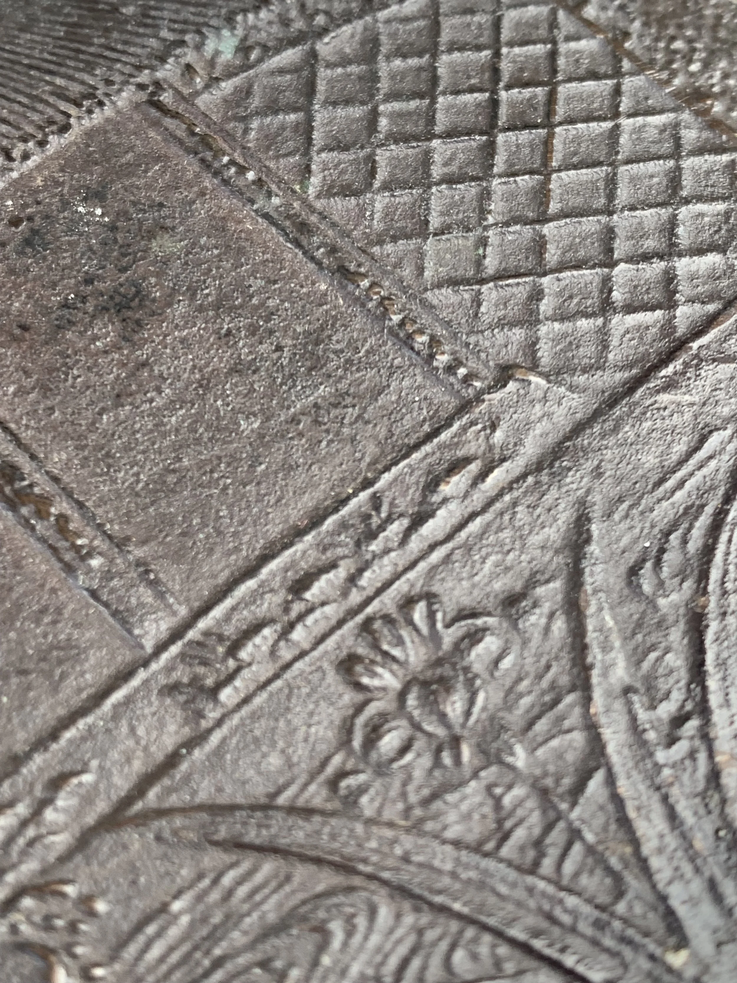 Close-up of a textured metal surface with geometric patterns and a floral design