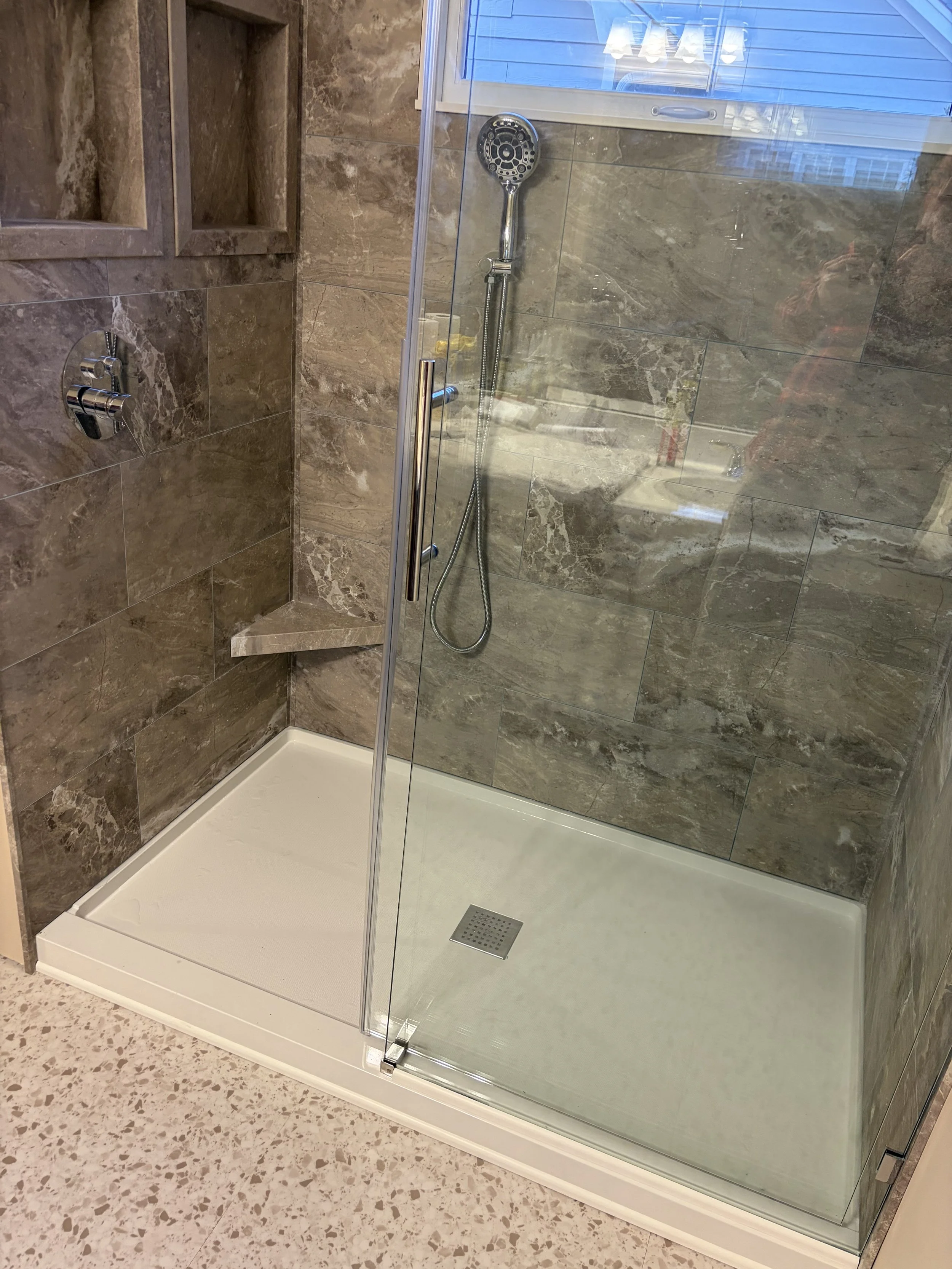 This beautiful grout-free vinyl tile on the shower wall is called Venetian Marble. Note the two recessed niches and the foot shelf.