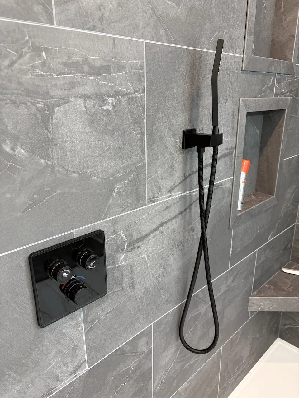 His & her recessed niches and a corner bench match the grout-free tile colors. We work with you to find the best location for such accessories.