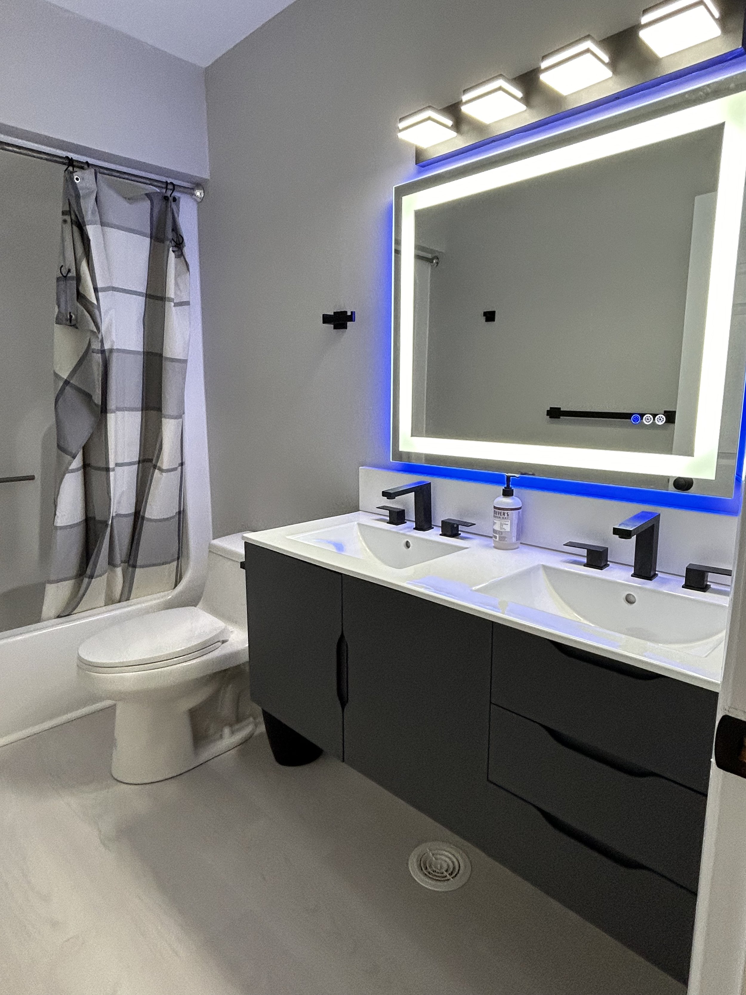 New flooring, toilet, vanity, lights, and mirrors transformed this bathroom