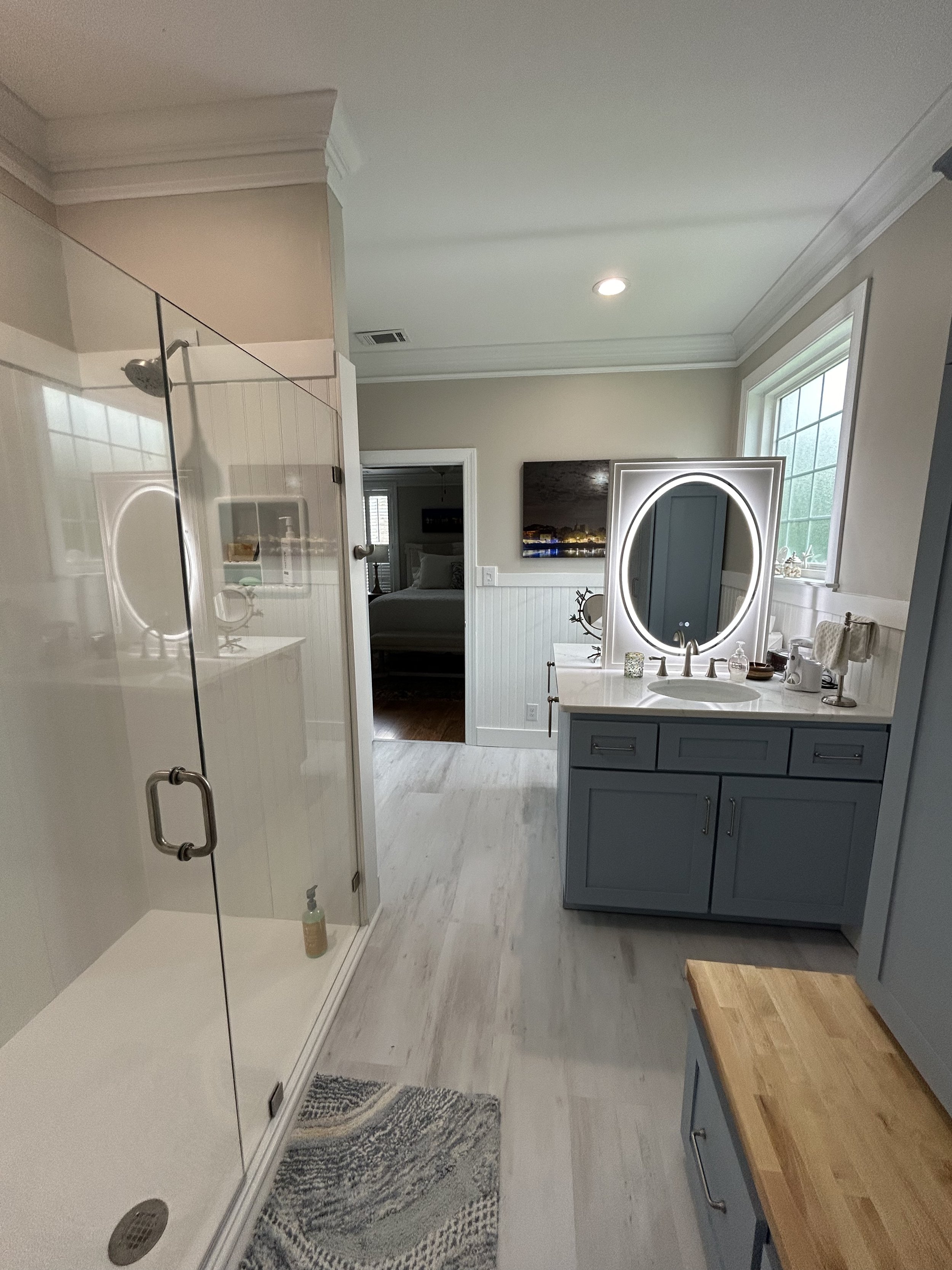 This beautiful renovation includes opposing vanities with a custom built lighted mirror wall. The shower walls are made of PVC bead-board.