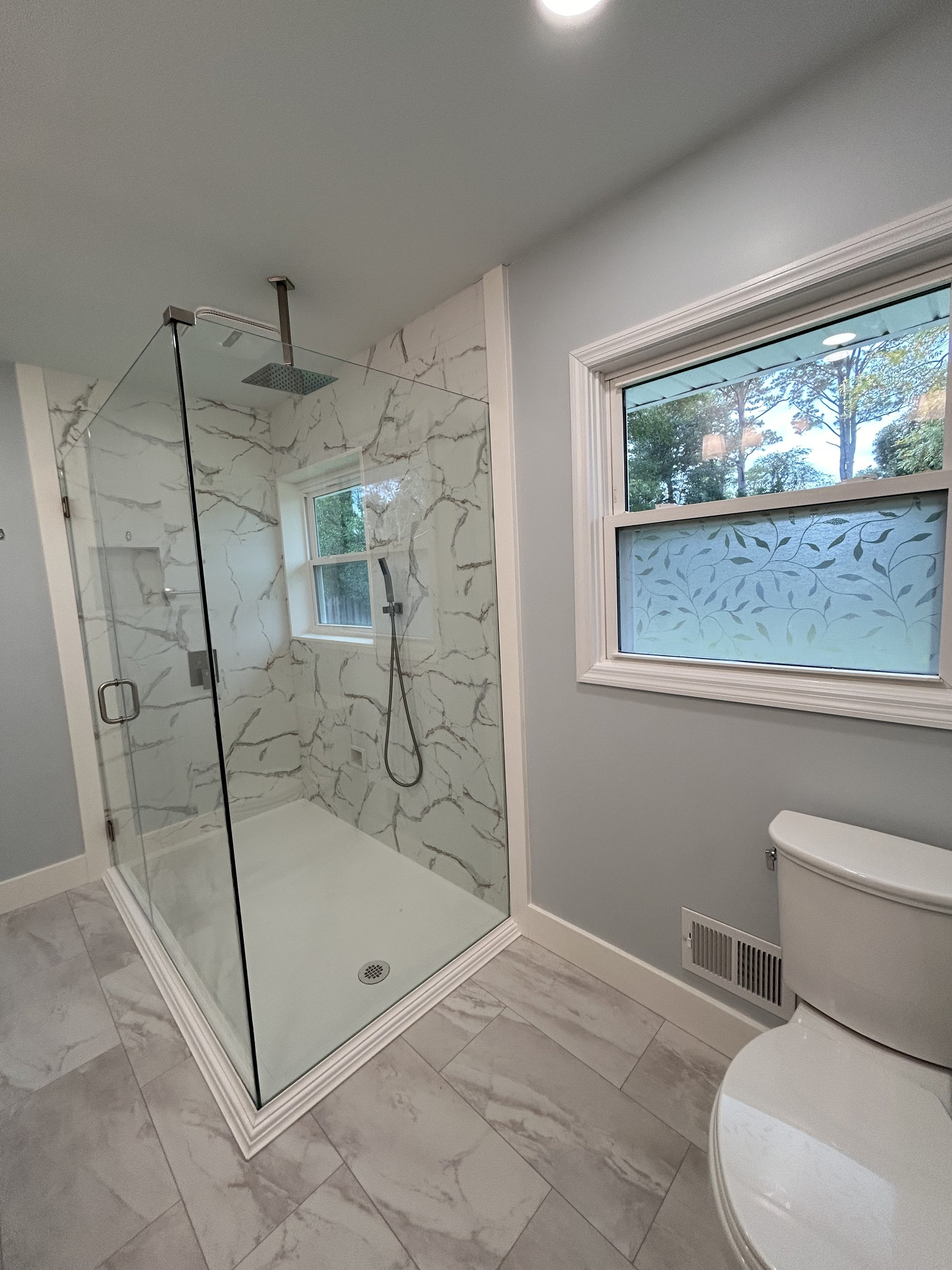 A 90 degree glass enclosure with vinyl wall tile and a custom-made non-slip, acrylic base with vinyl floor tile