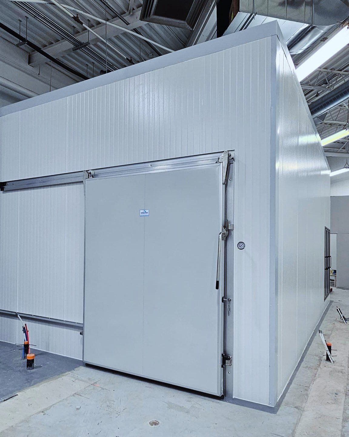 Industrial cold storage unit or walk-in freezer with a large sliding door inside a warehouse.