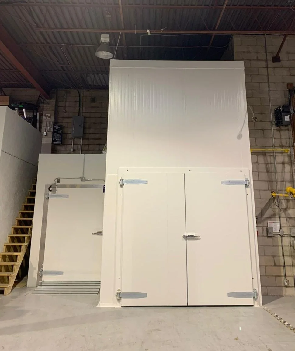 Industrial heat storage tank with insulated doors and a staircase to the left, in a warehouse setting.
