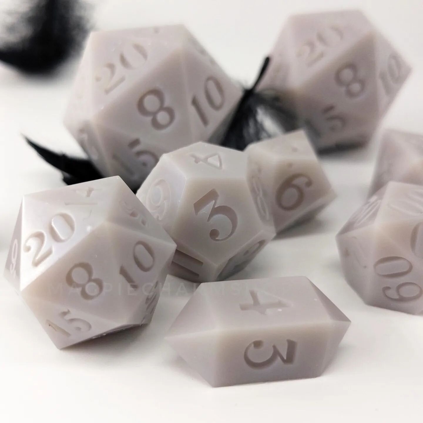 This set is proving to be nearly impossible to photograph well. Yes, it's opaque. Yes, it's grey. But there's a TINY shimmer that hits the edges in the sunlight; interference blue and violet that gives these dice a moonstone effect. Subtlety doesn't 