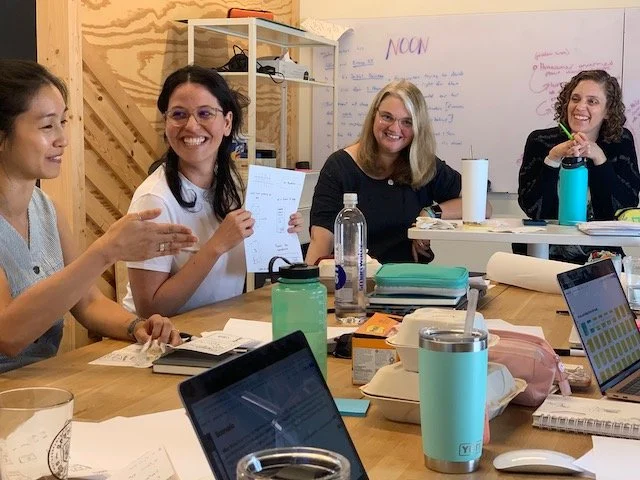 A collaborative moment captured as AC4D students share ideas around a classroom table.