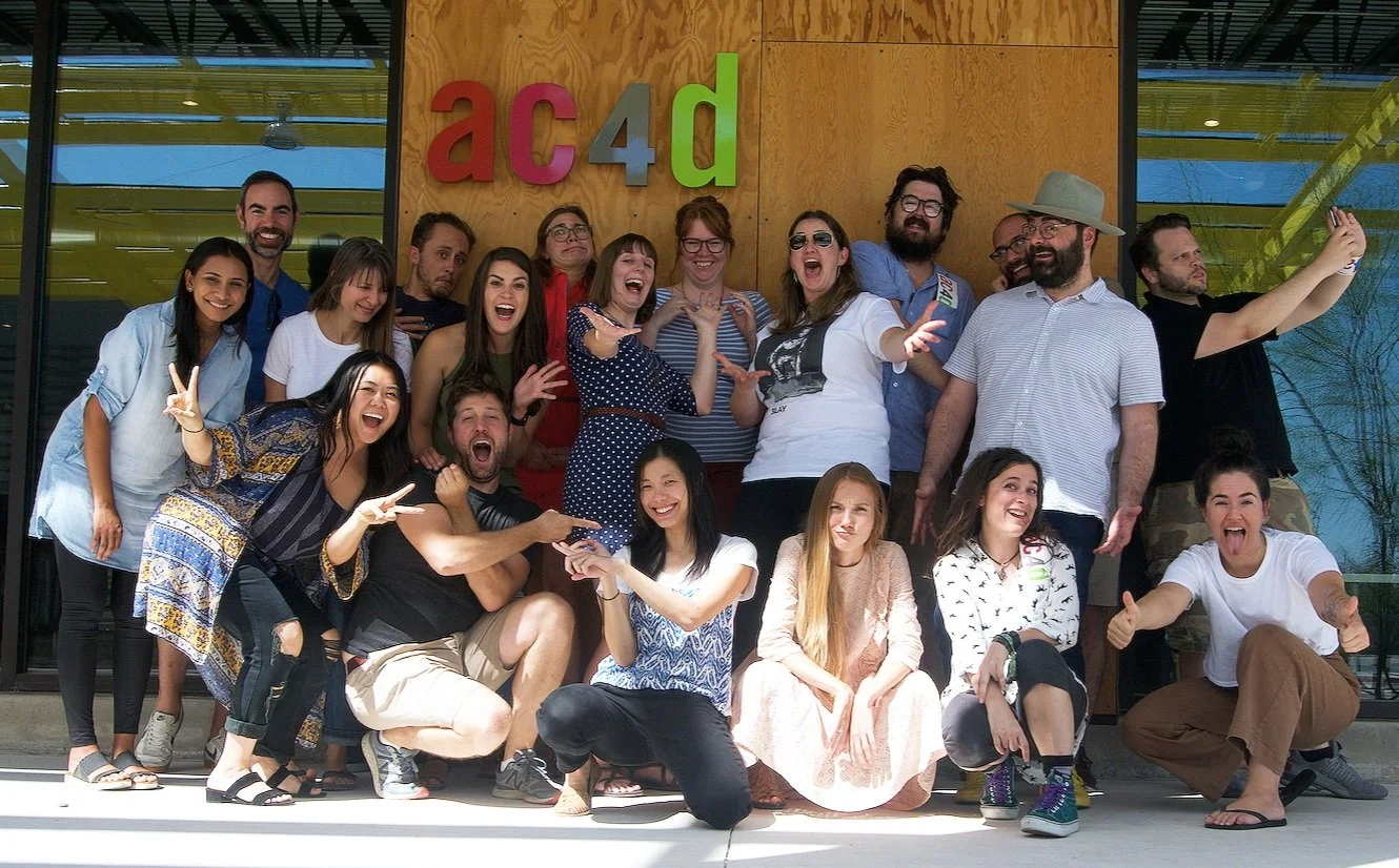 A diverse group of students and faculty members smiling together at Austin Center for Design.