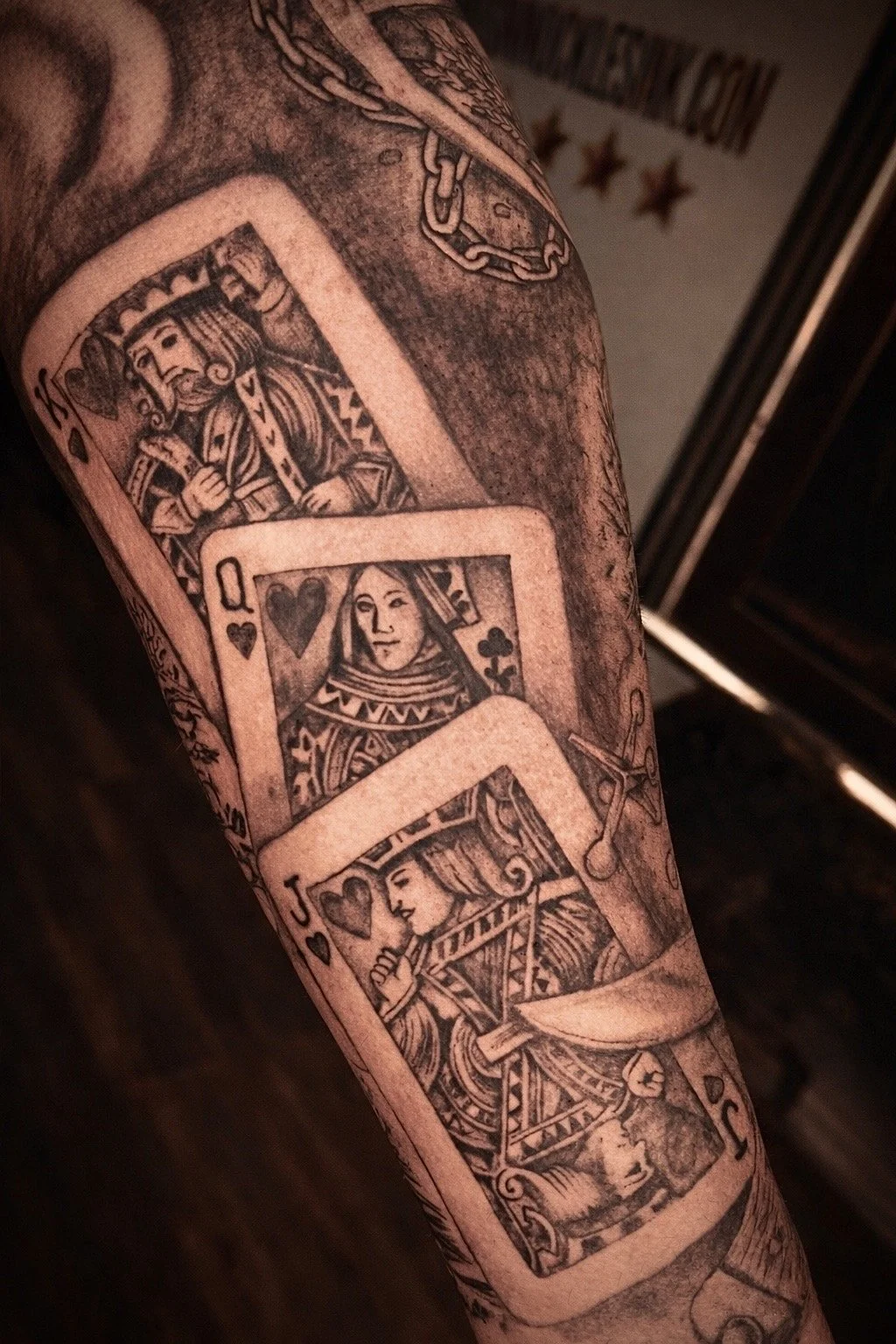 Black and grey playing card tattoo featuring King, Queen and Jack in detailed sleeve work by Bronx NYC professional tattoo artist.