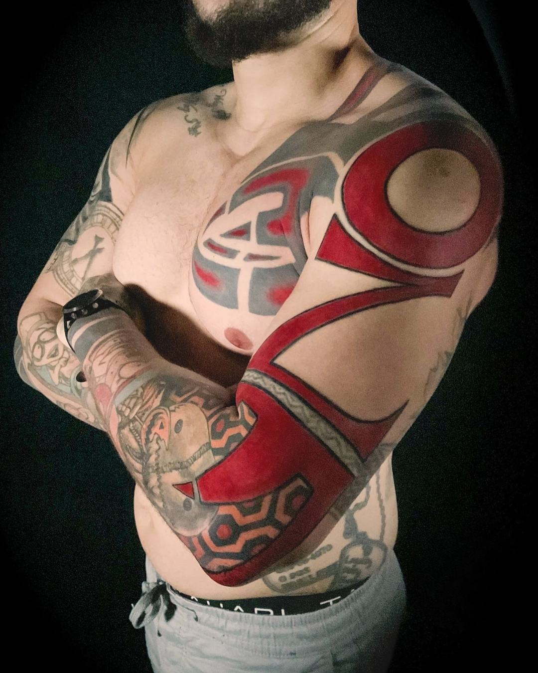 Stephen King inspired chest and arm tattoo with red and black biomechanical horror design and abstract bold patterns
