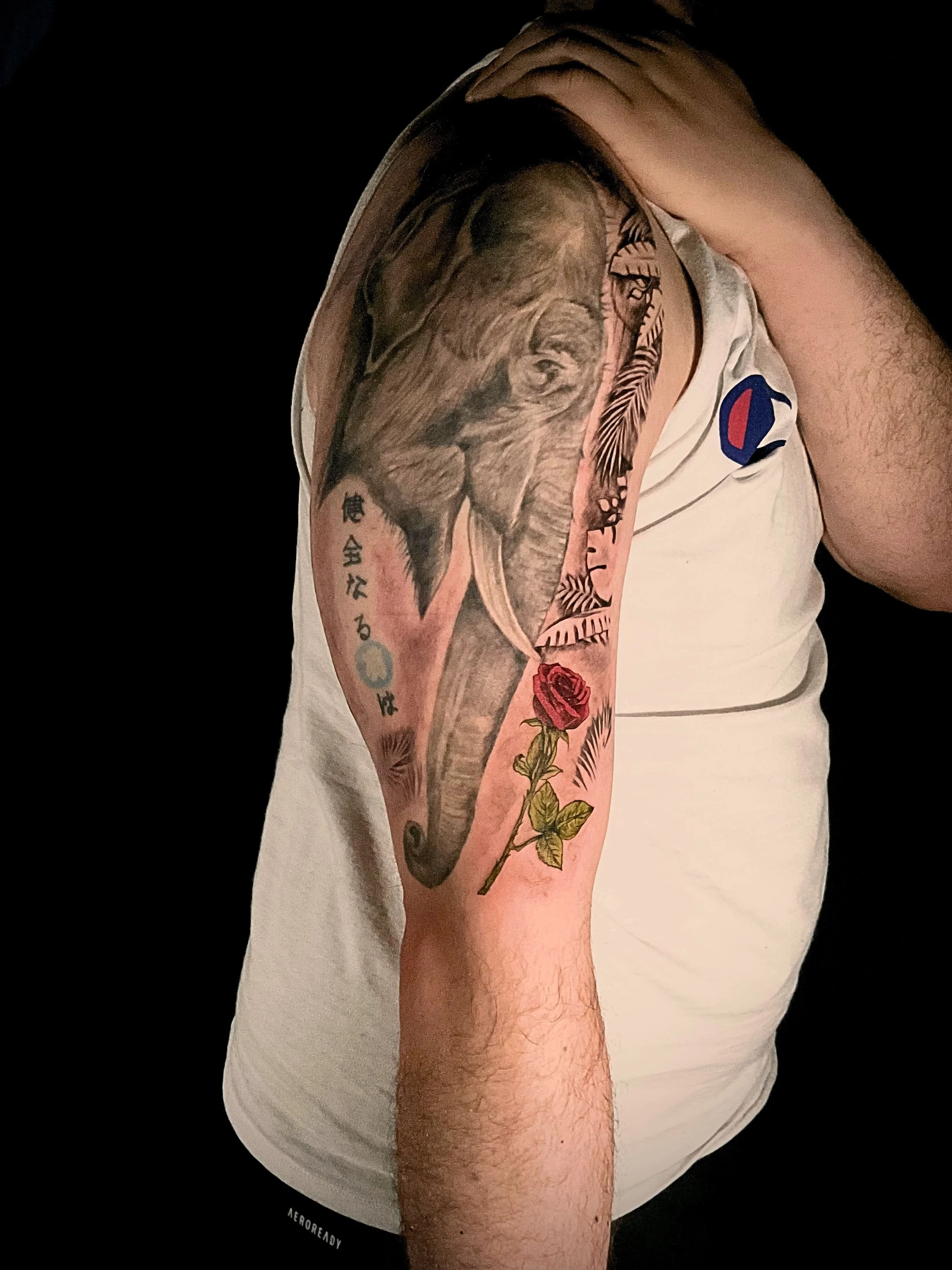 A detailed black and grey realism elephant tattoo featuring textured shading, ornamental linework and a red rose accent. This custom upper arm piece blends strength, wisdom and symbolism, created by professional, Bronx NYC tattoo studio