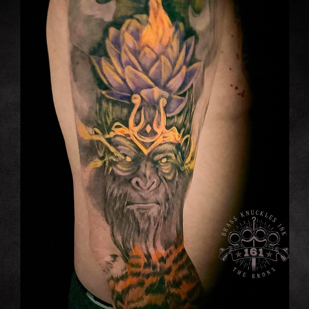 A powerful custom forearm tattoo featuring a mythical monkey king crowned with a glowing lotus, designed and inked at Brass Knuckles Ink Tattoo Studio.