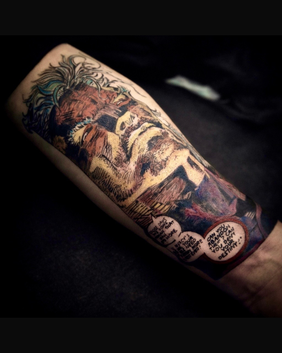 This striking forearm tattoo captures a dramatic comic book-style portrait of a dark, brooding superhero rendered in rich, shaded colors and fine ink detail. Styled with cross-hatching and expressive linework, the design includes thought-provoking sp